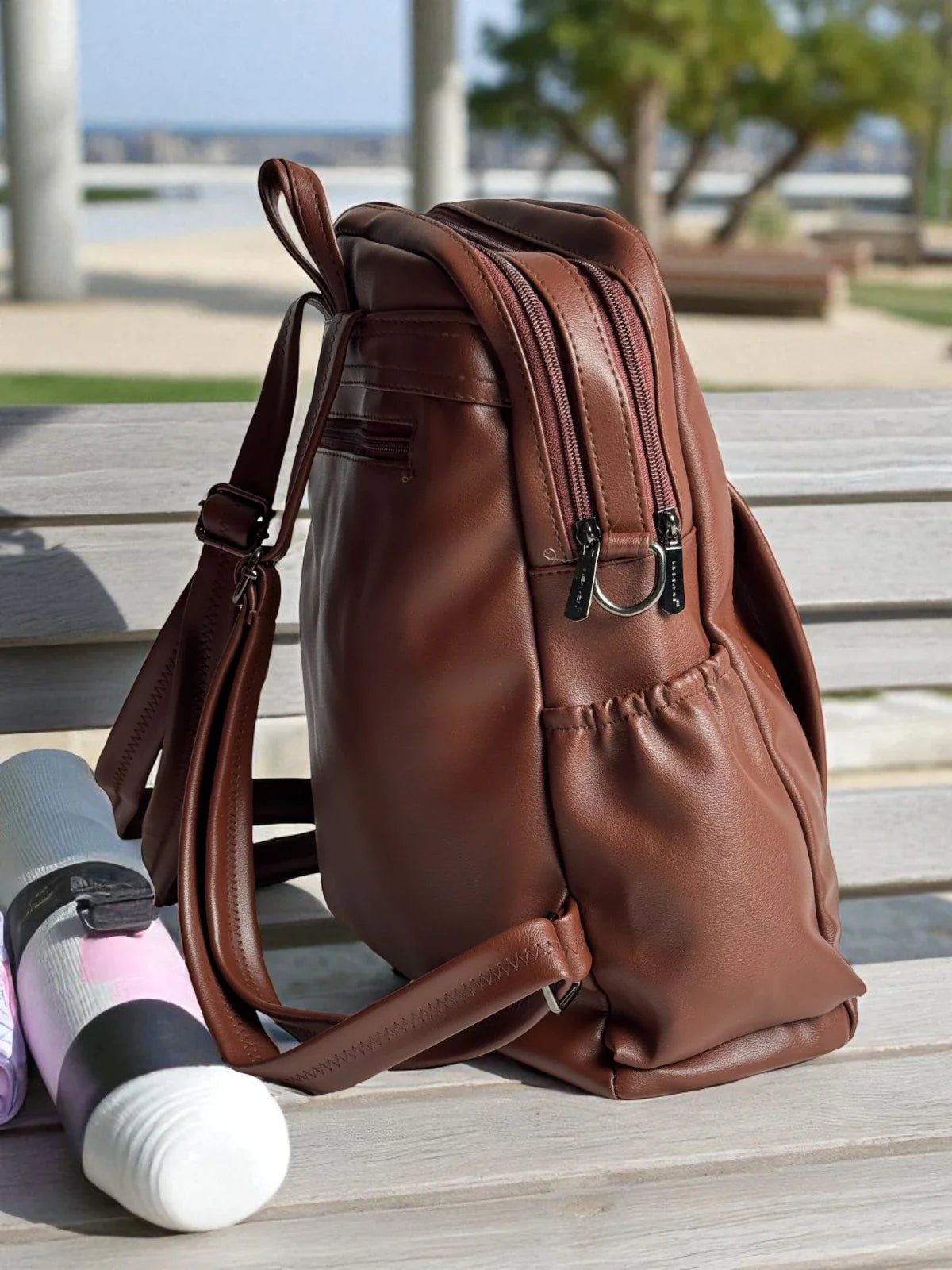 Tarani brown PU leather backpack side view with zip compartments