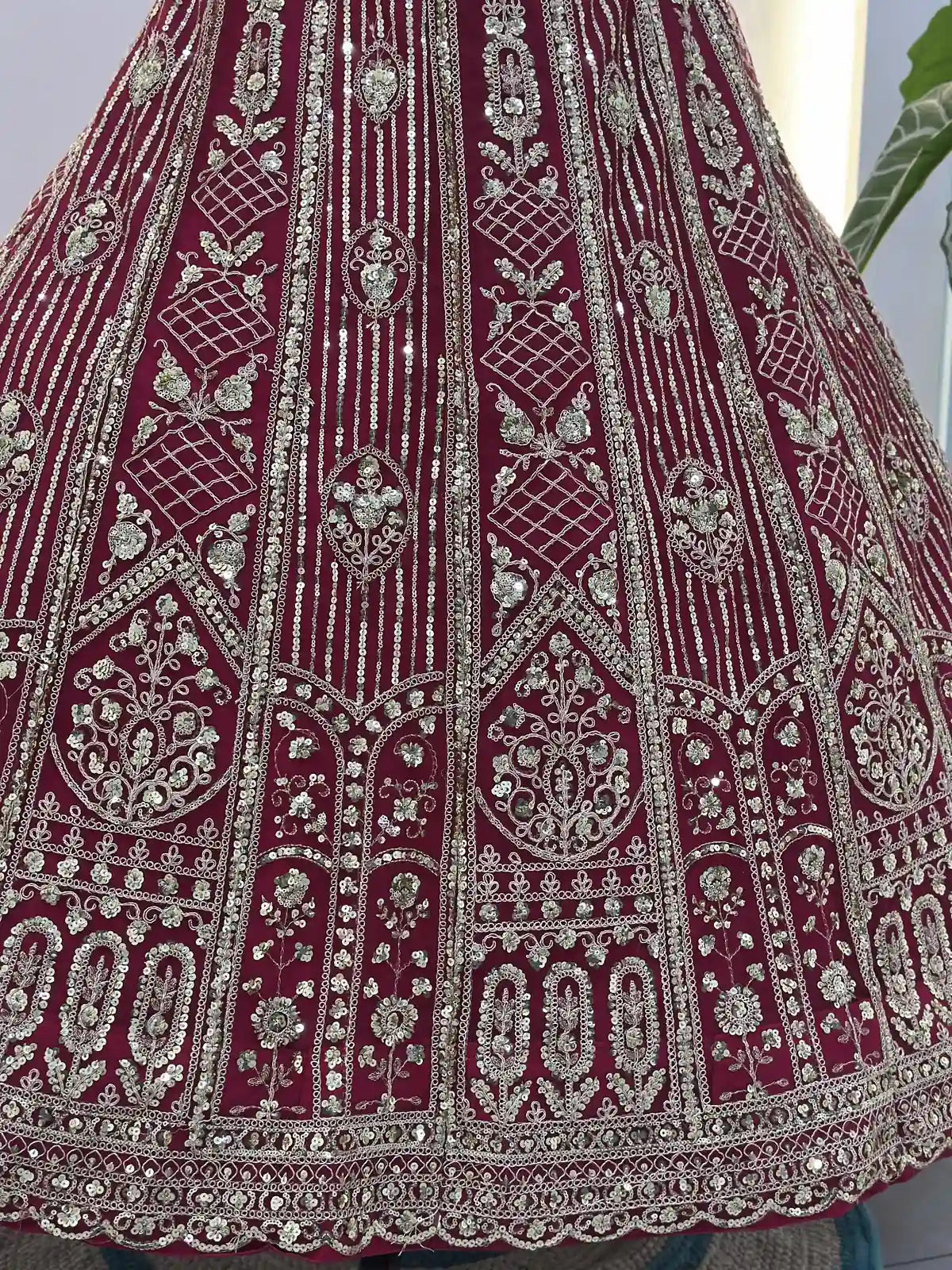 Closeup of detailed embroidery and sequin work on red butterfly net lehenga from Tarani