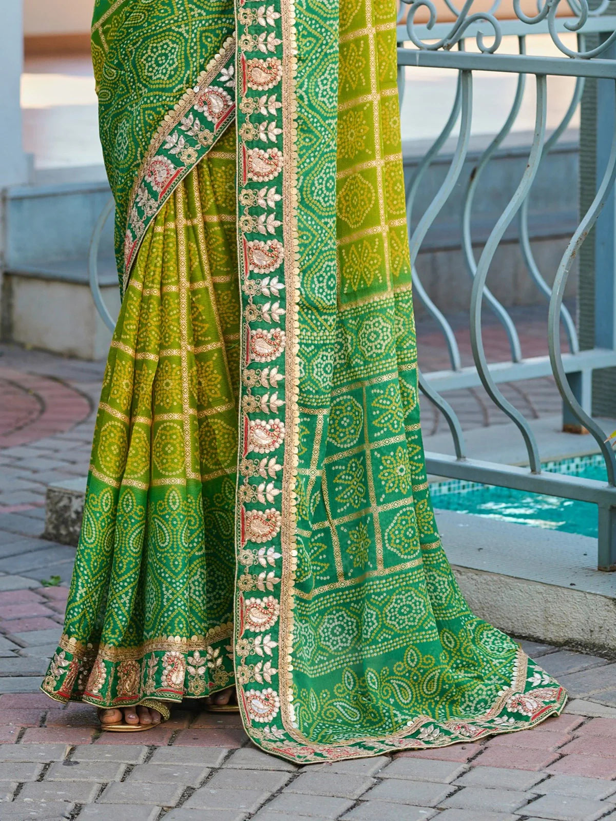 Tarani green moss chiffon saree fabric closeup with floral zari border and bandhani-inspired print