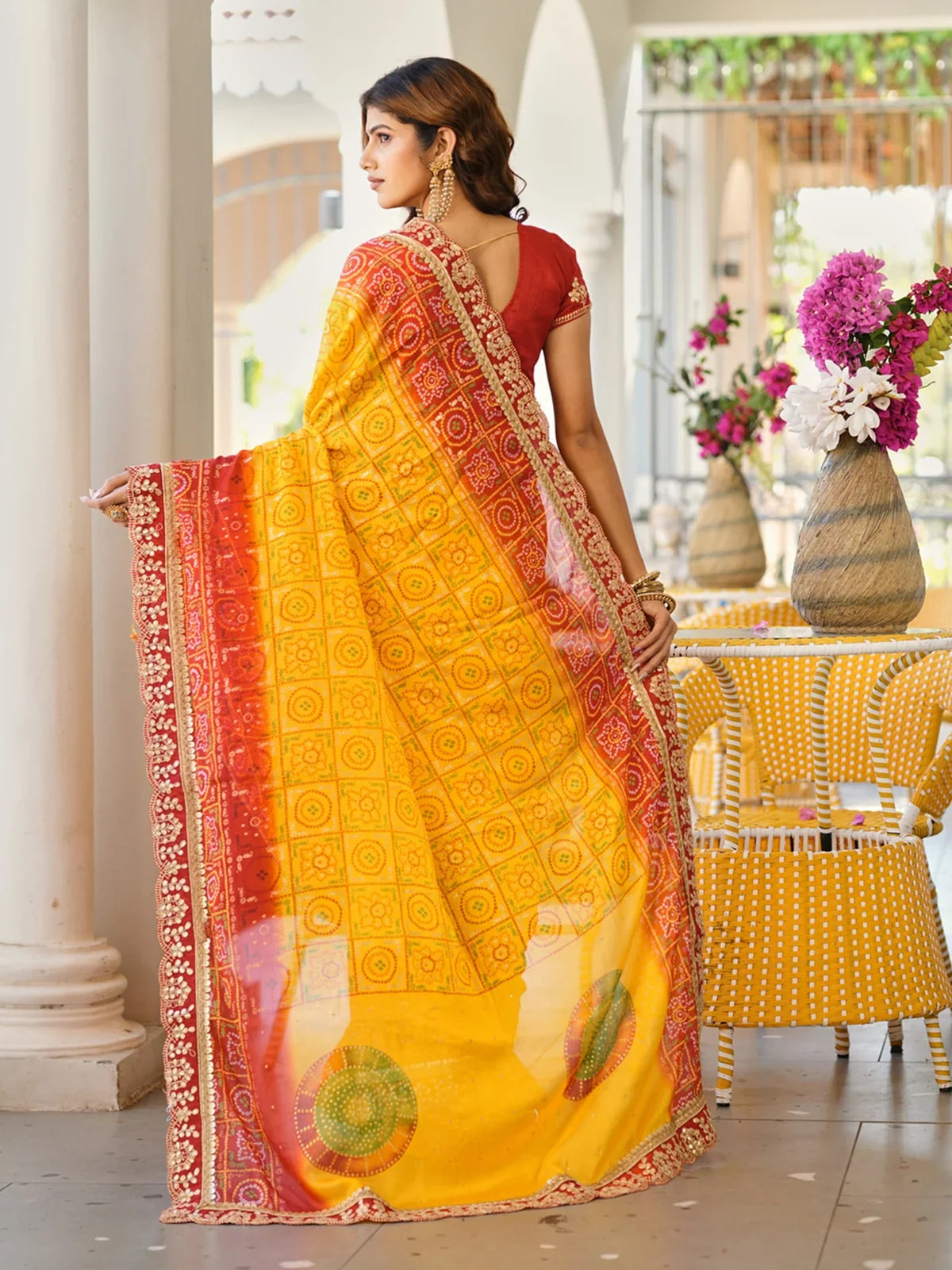 Back view of Tarani yellow and red chiffon saree with detailed festive patterns and pallu