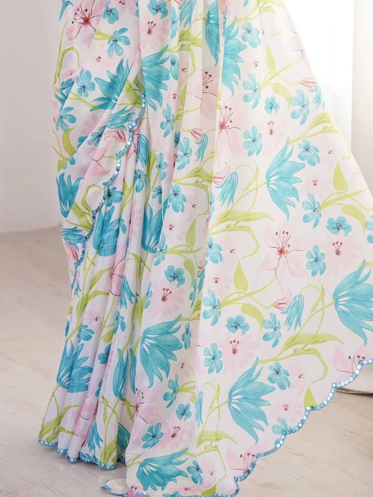 Tarani saree closeup of blue and pink floral print with green leafy accents on soft white base
