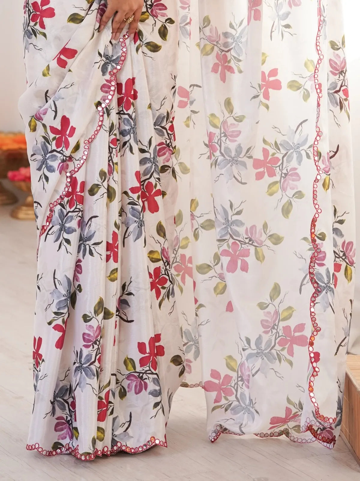 Tarani floral pallu closeup view with red mirror work border on white chinnon saree