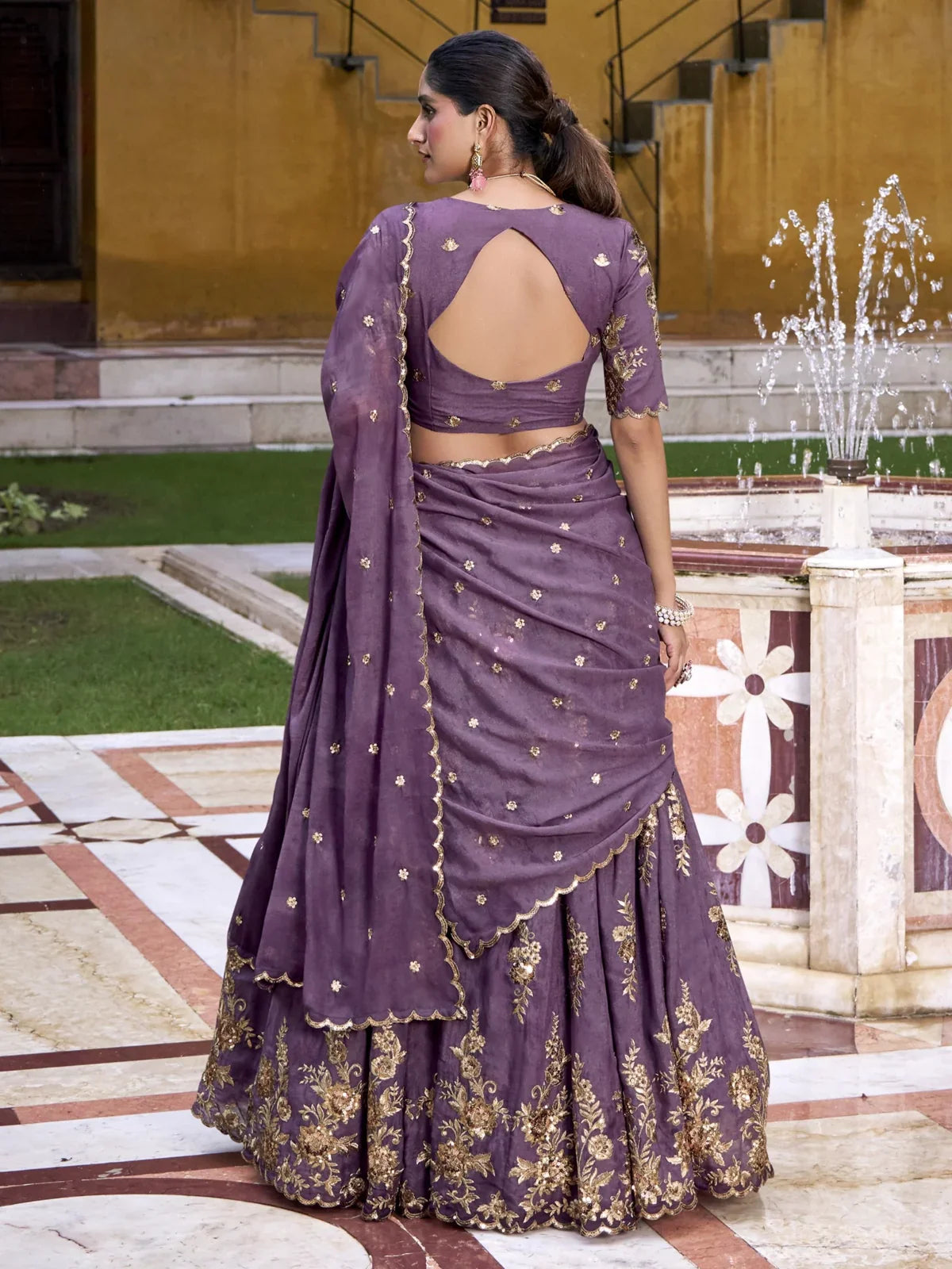 Tarani lehenga back pose with designer cut blouse and draped dupatta in purple chocolate crush fabric