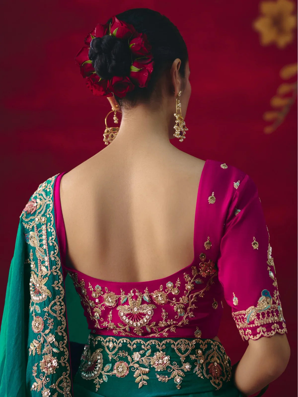 Tarani festive green saree back blouse view with contrast magenta embroidery and floral bun styling