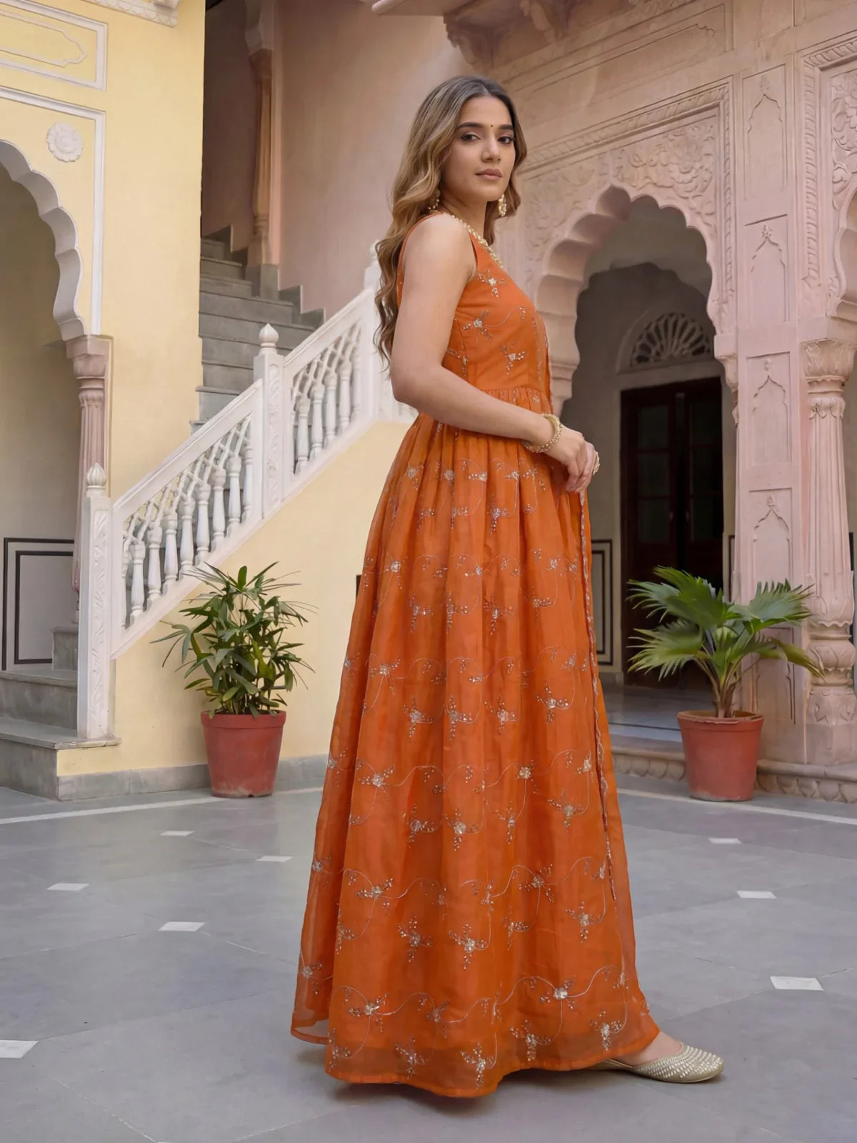 Tarani side pose of orange embroidered fandy silk dress with graceful flow
