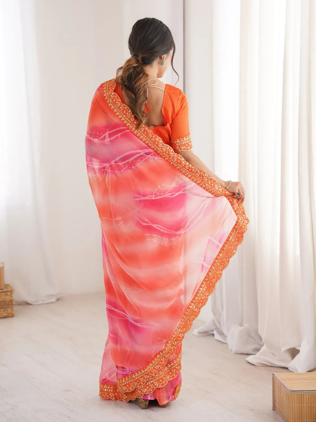 Tarani orange georgette saree back view highlighting pallu and scallop border