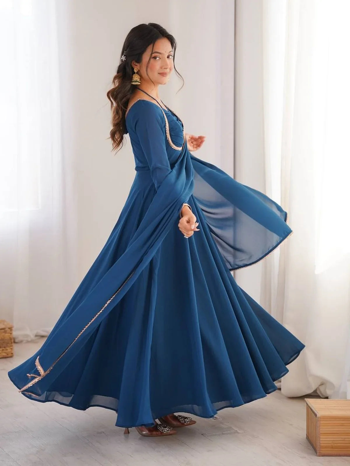 Side profile of flowy blue georgette party gown with lace border dupatta by Tarani