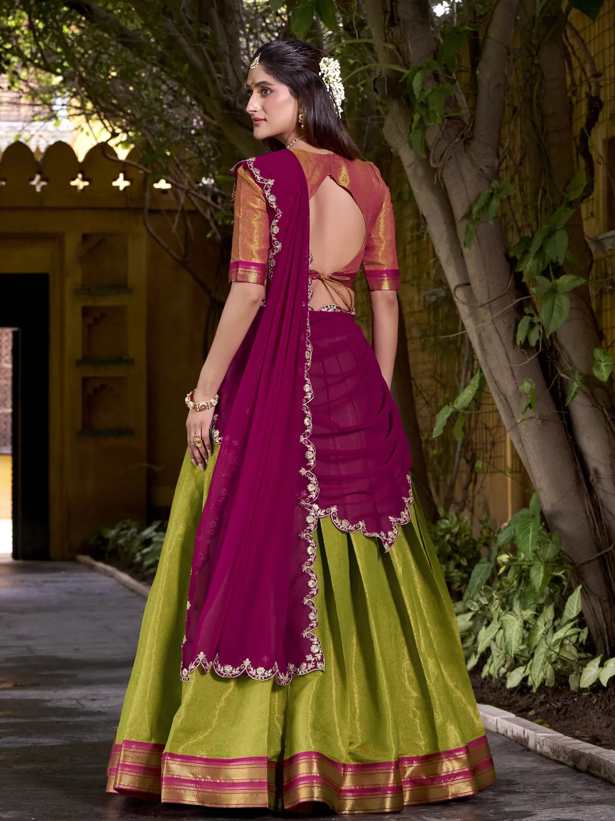 Tarani green lehenga back pose with magenta dupatta and open back blouse view