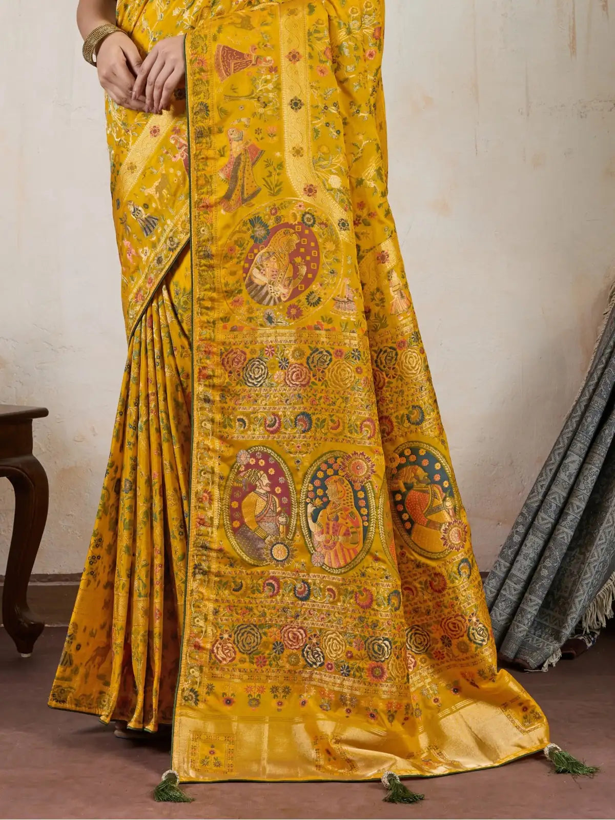 Tarani yellow silk saree grand pallu view showcasing meenakari motifs and tassels