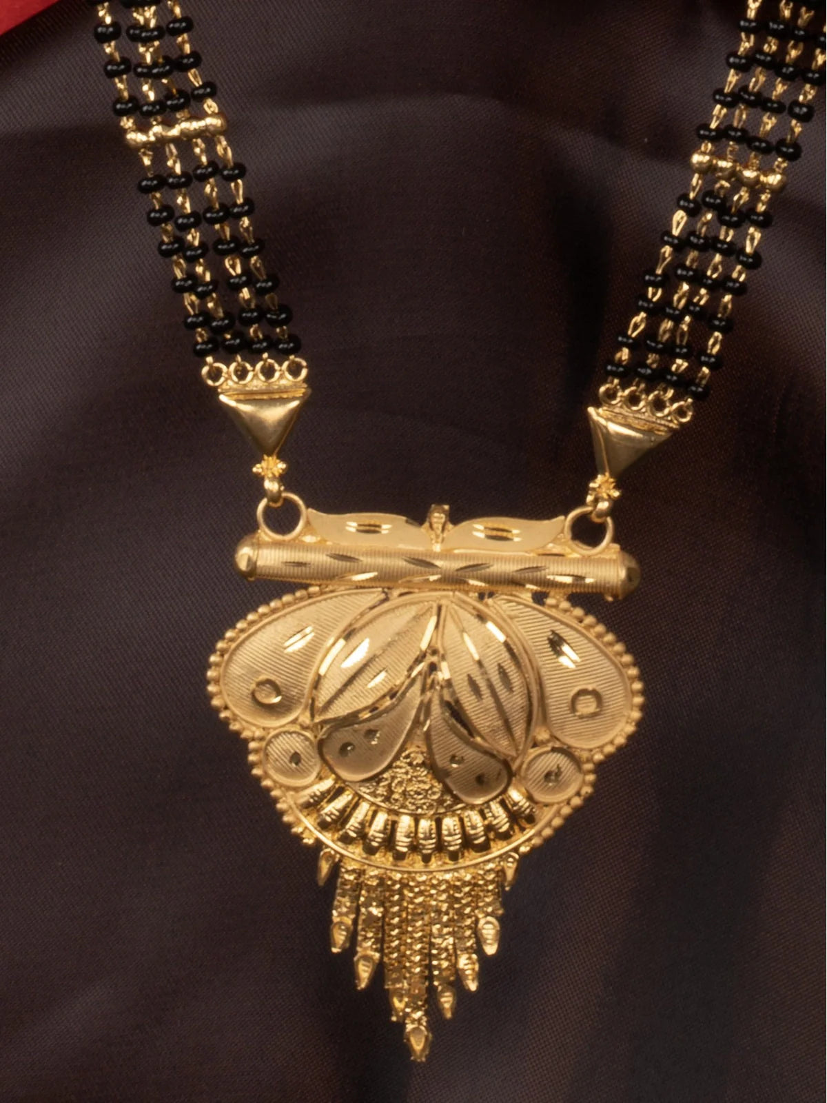 Tarani closeup of gold plated mangalsutra pendant with intricate detailing and black beads