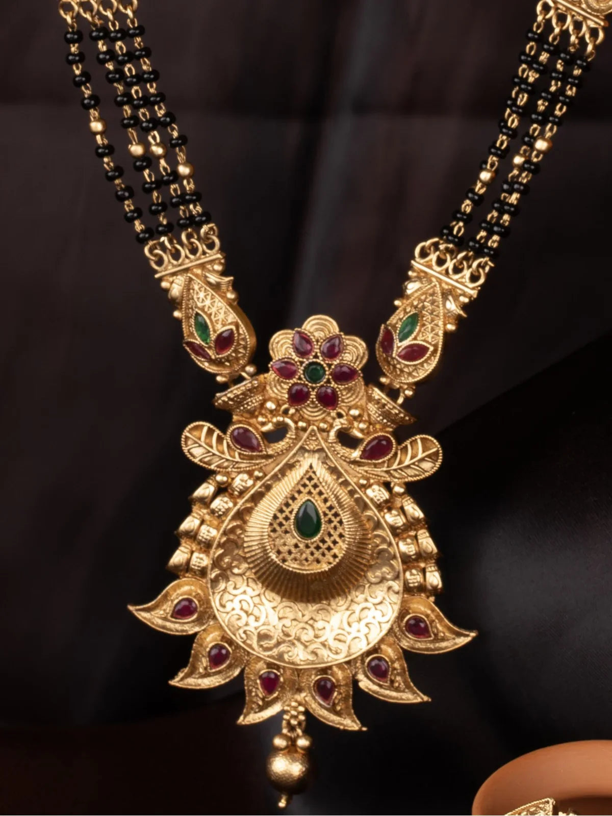 Tarani closeup view of gold plated mangalsutra pendant with stone detailing and black beads