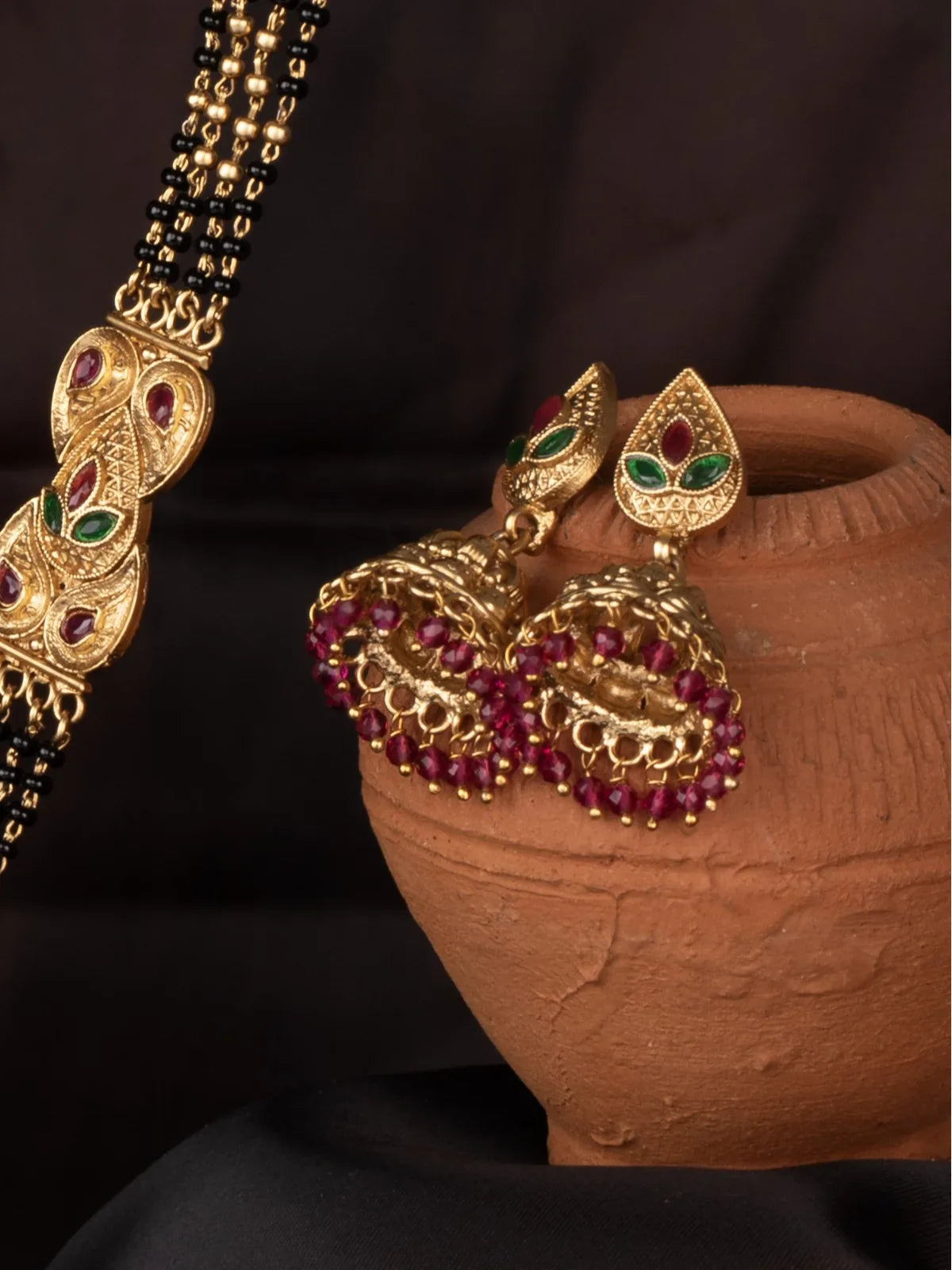 Tarani side view of mangalsutra earrings with gold finish and red green stone work