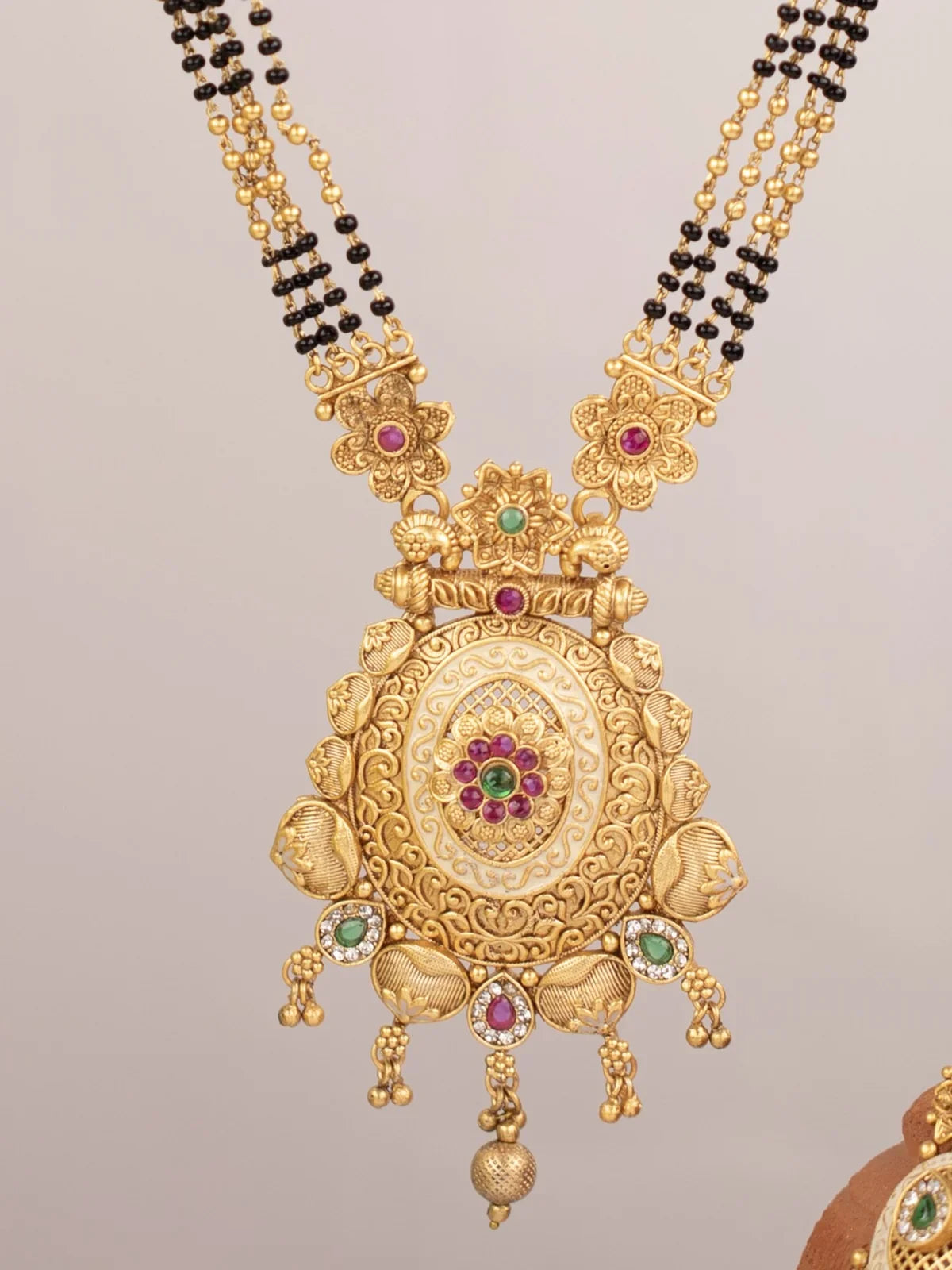 Tarani closeup view of gold plated stone studded mangalsutra pendant with intricate detailing