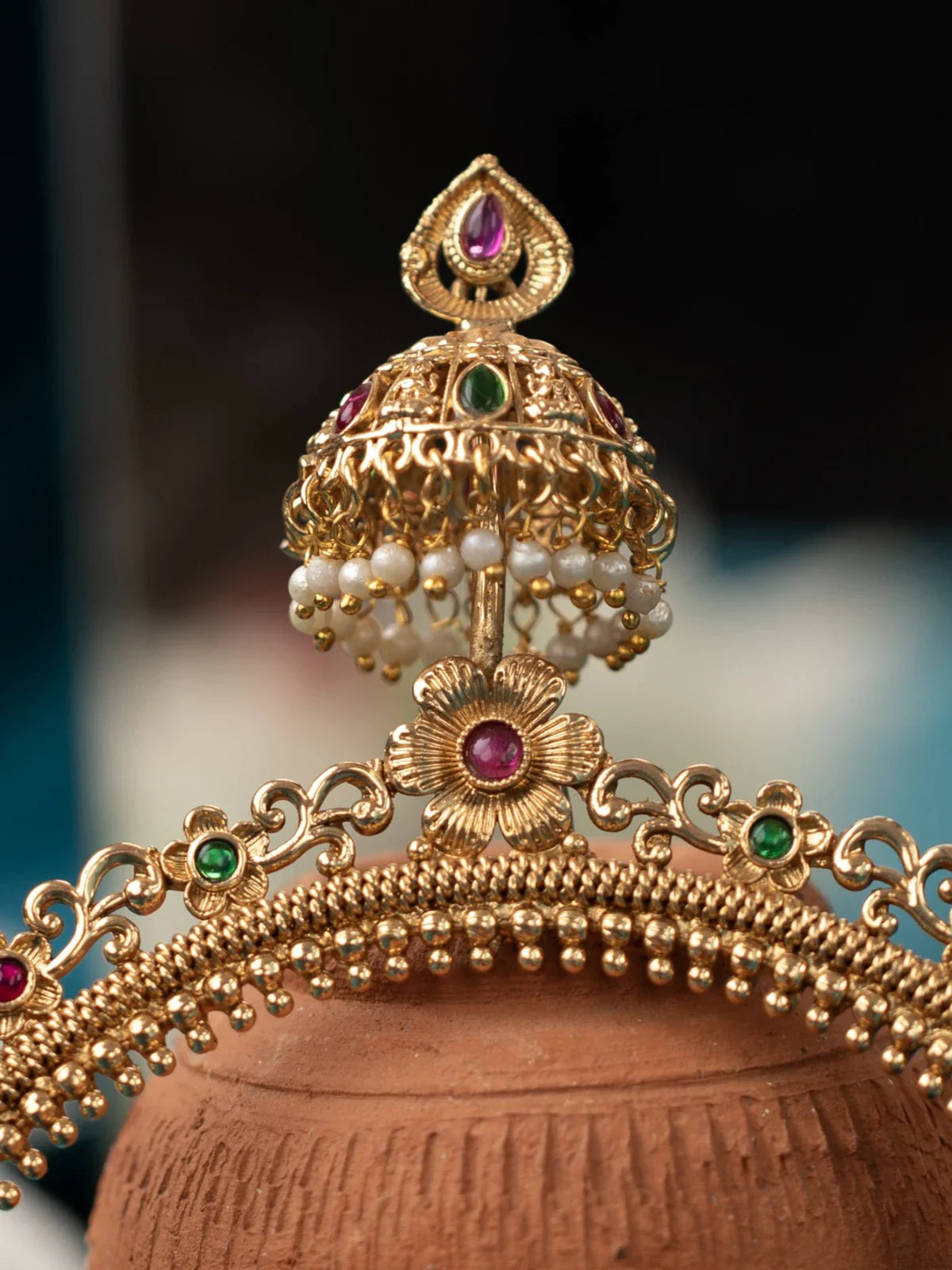 Tarani closeup view of gold plated mathapatti with colorful stones and pearl detailing for festive occasions