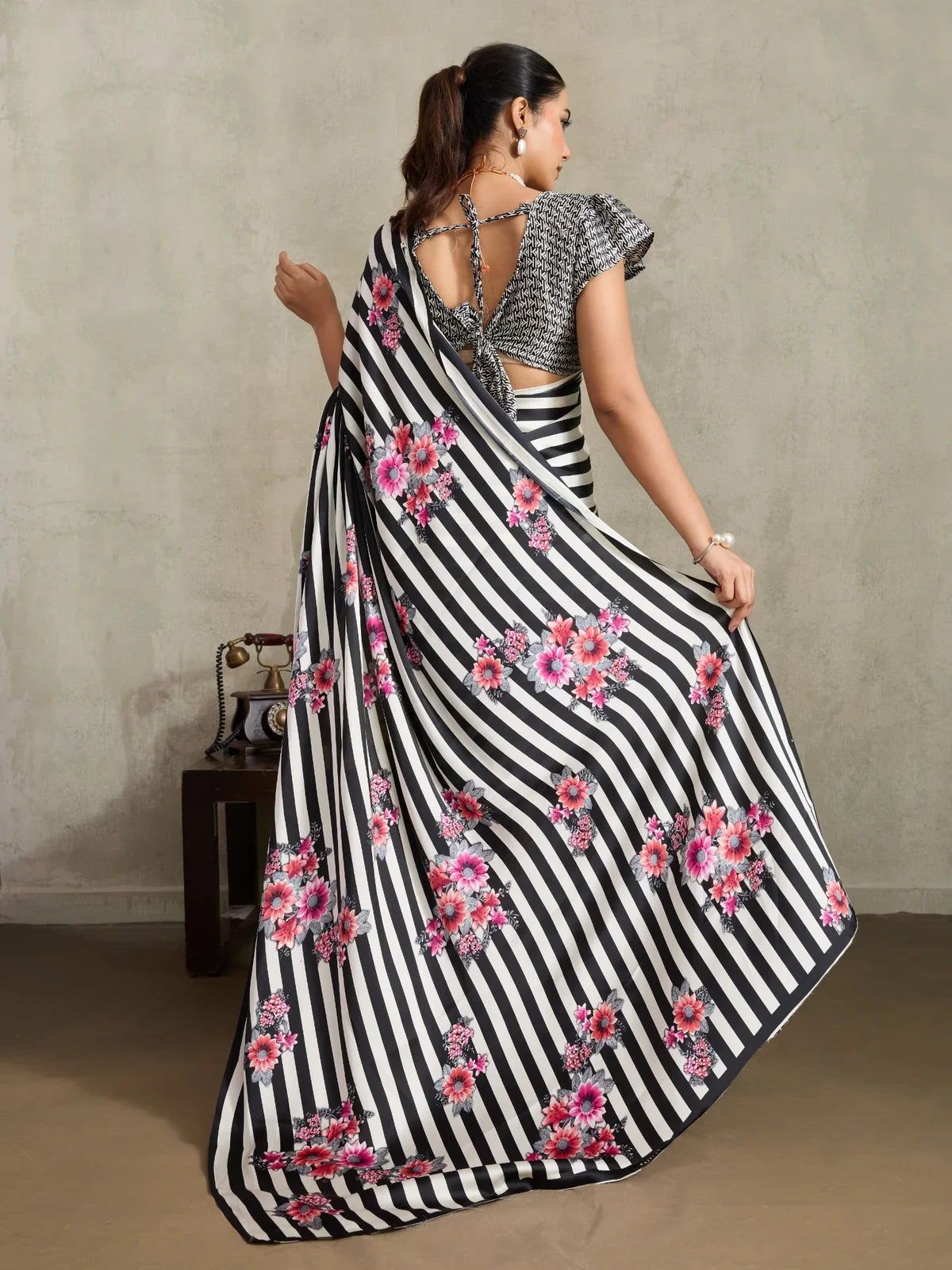 Tarani saree model back pose showing stylish tie-up blouse and black striped floral pallu in motion