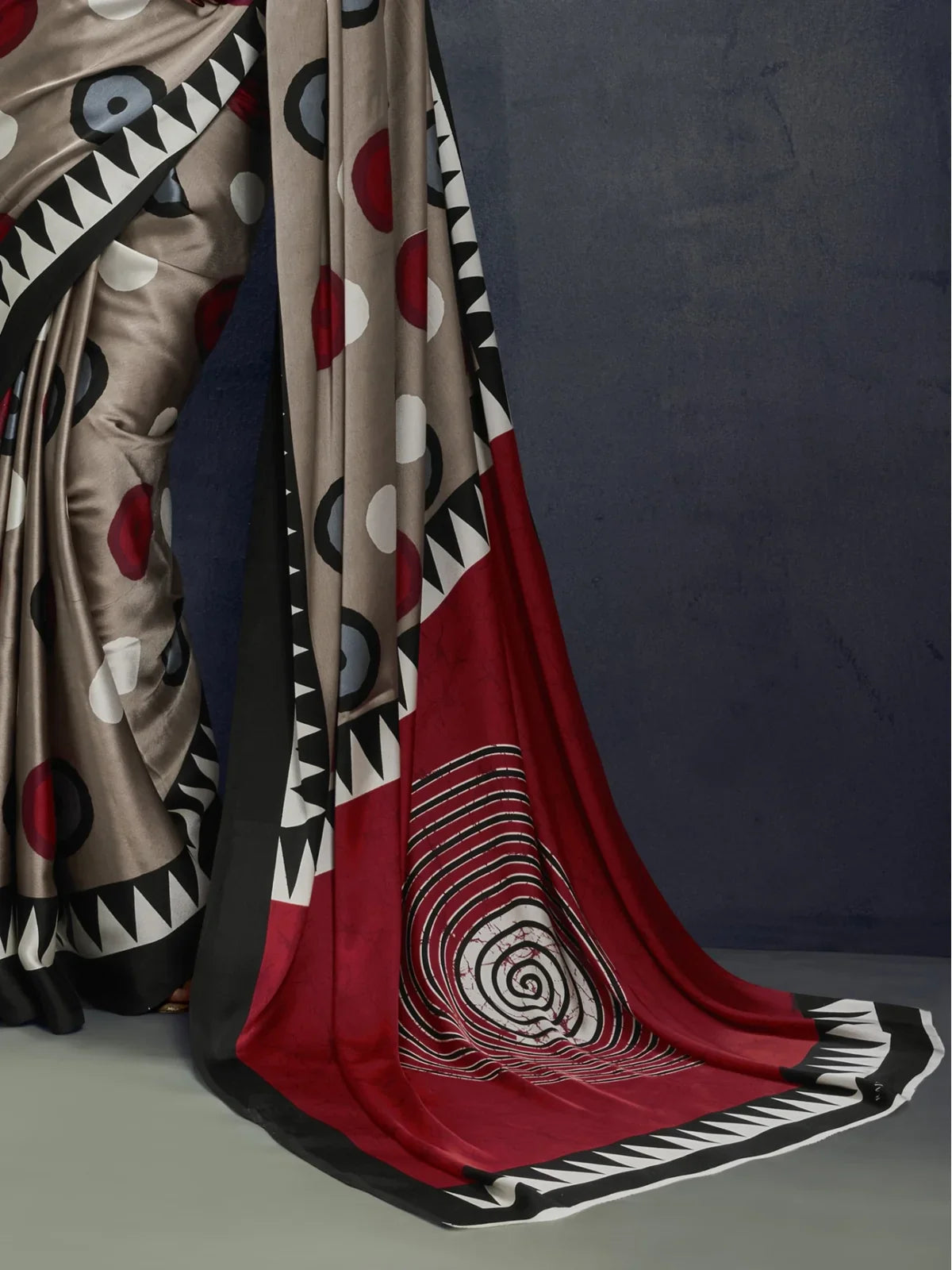 Tarani modal satin saree closeup showing pallu design with red and black swirl pattern