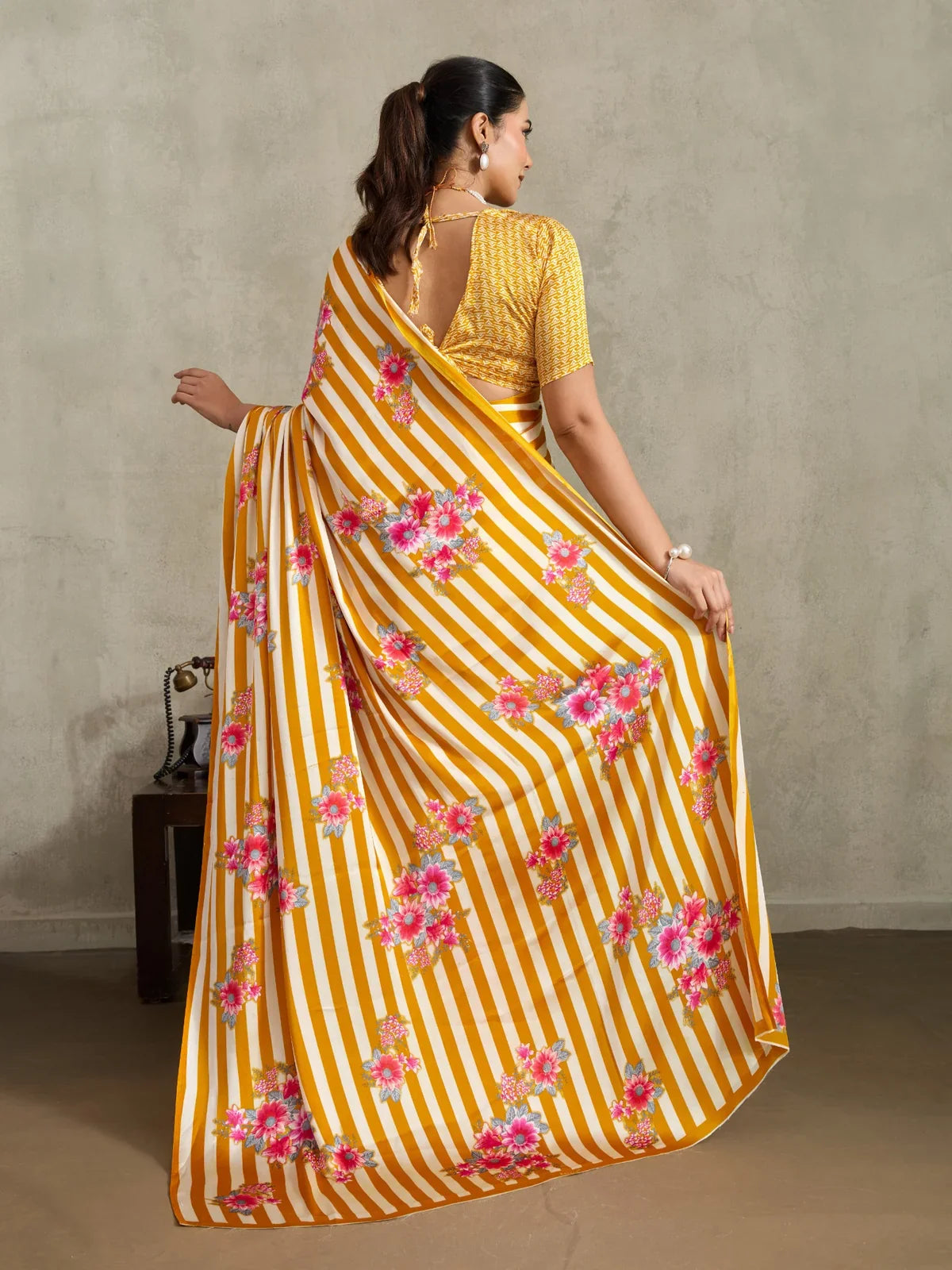 Tarani back view showing full pallu with vertical mustard stripes and blooming pink floral motifs