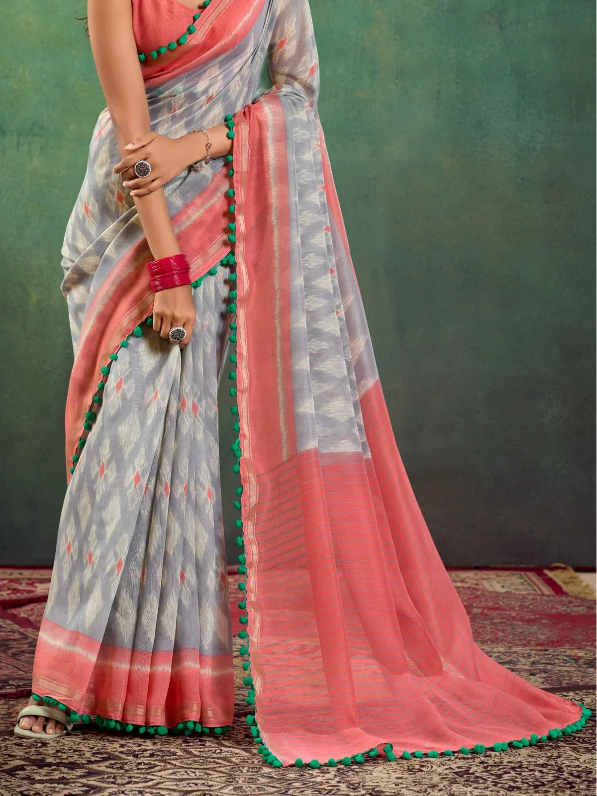 Tarani mul mul cotton saree pallu view showing peach and grey woven pattern with green tassels