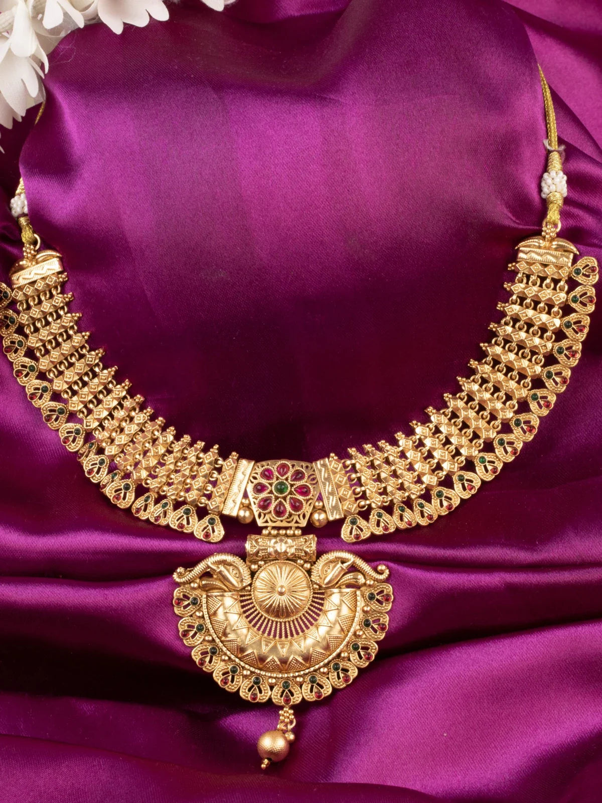 Tarani gold plated necklace set closeup-view with intricate red and green stone detailing
