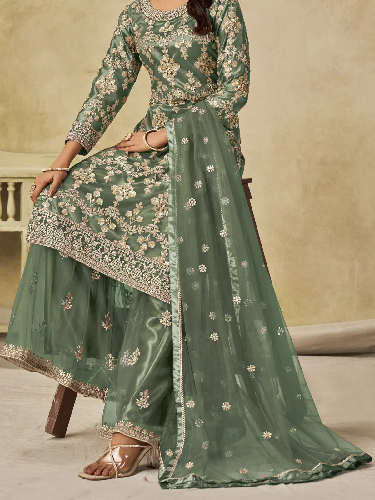 Tarani green net sitting pose showcasing palazzo embroidery and dupatta design