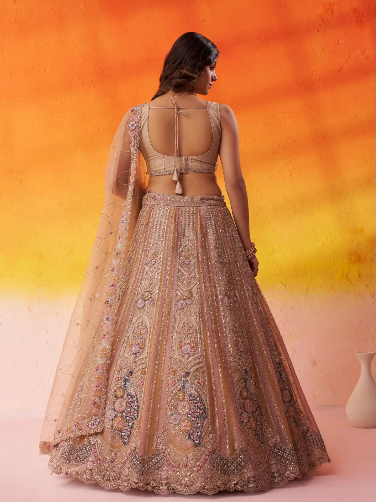 Tarani back view of beige net lehenga showing tie-up blouse design and dupatta drape