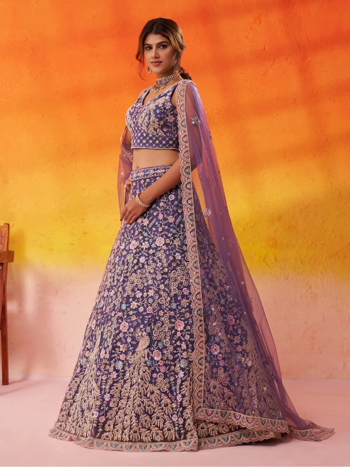 Tarani side pose of purple net lehenga with intricate floral and peacock detailing
