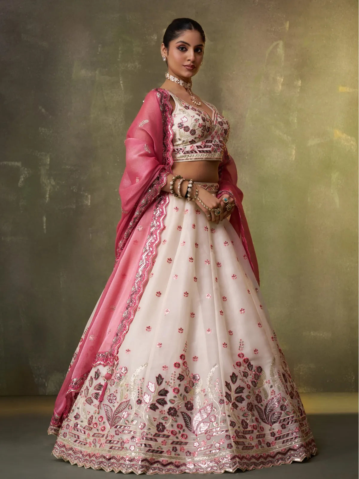 Tarani cream lehenga with pink dupatta and side pose showing embroidery details