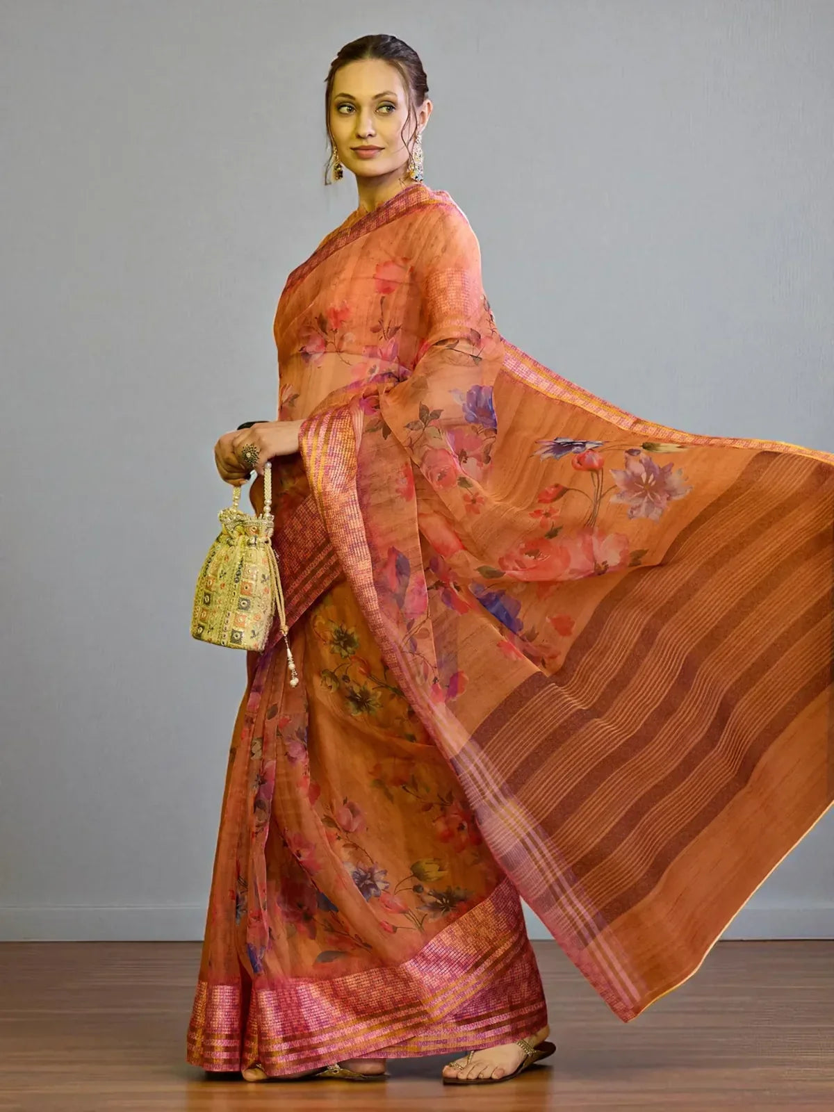 Tarani full view of orange floral organza saree with contrast pink border and elegant fall
