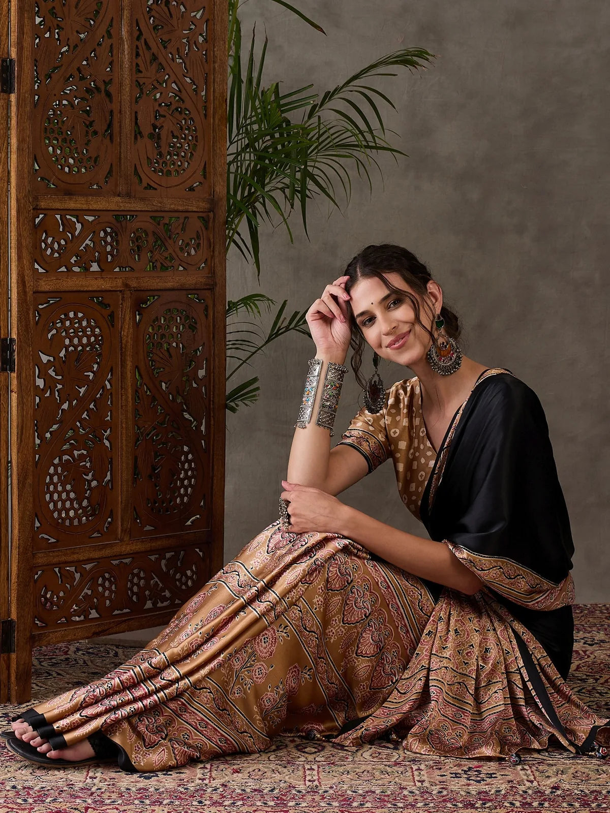 Tarani Dharika black semi modal satin printed saree seated side pose with elegant border