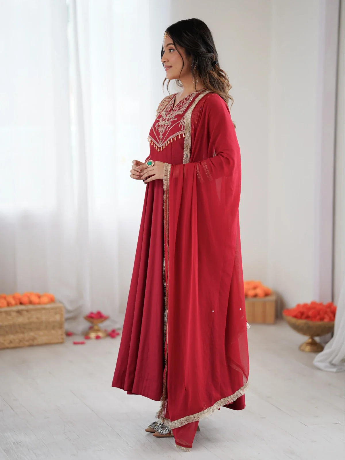 Tarani red Roman silk Anarkali gown side view with lace bordered dupatta and golden heels
