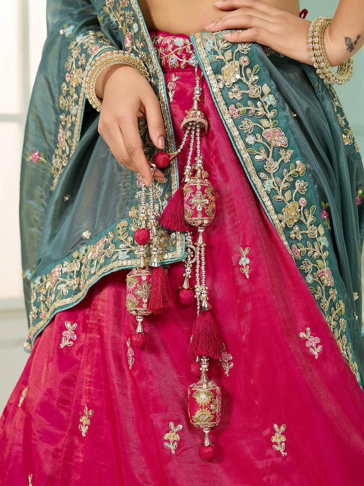 Tarani closeup of embroidery and handmade tassels on pink silk lehenga