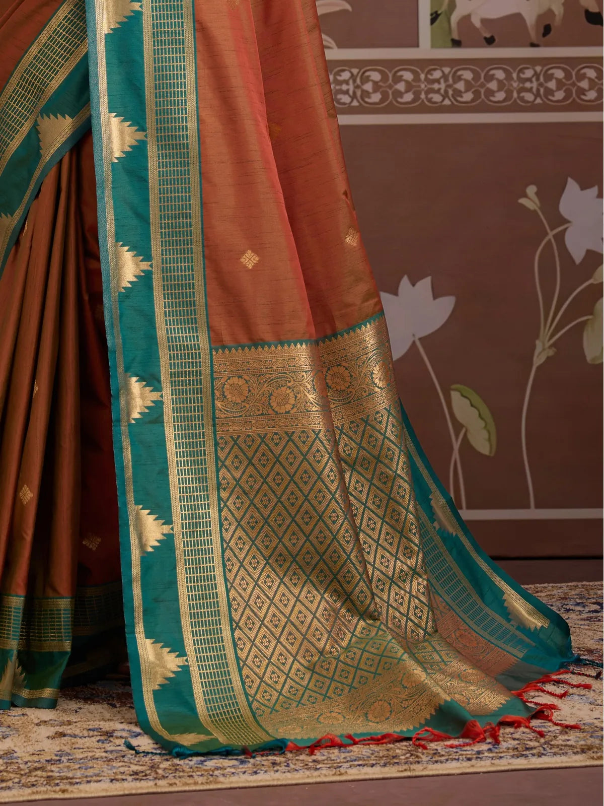Tarani designer silk saree pallu in green with gold detailing and red tassels in focus