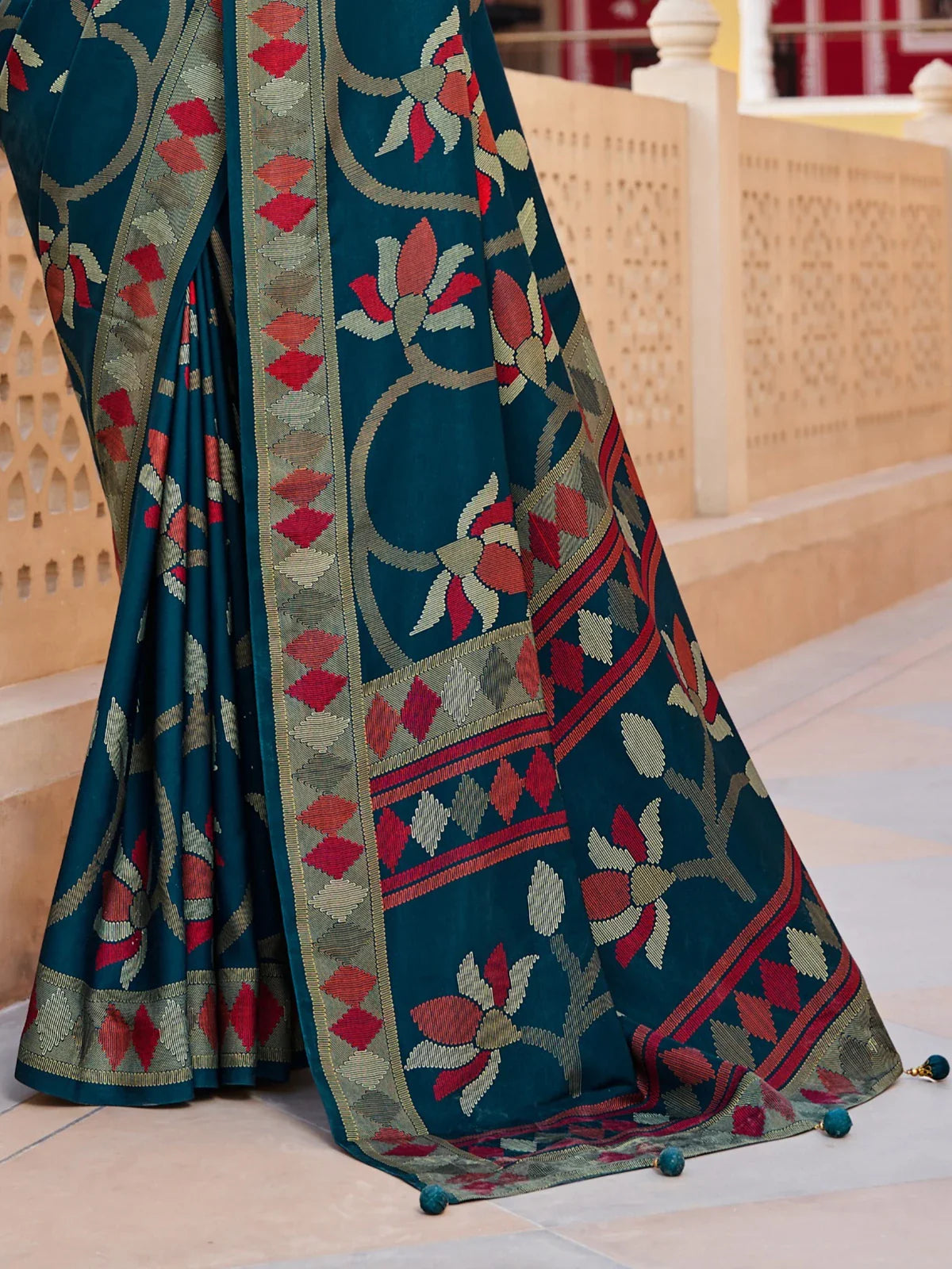 Tarani pallu view of festive green saree with bold red floral woven patterns and tassels