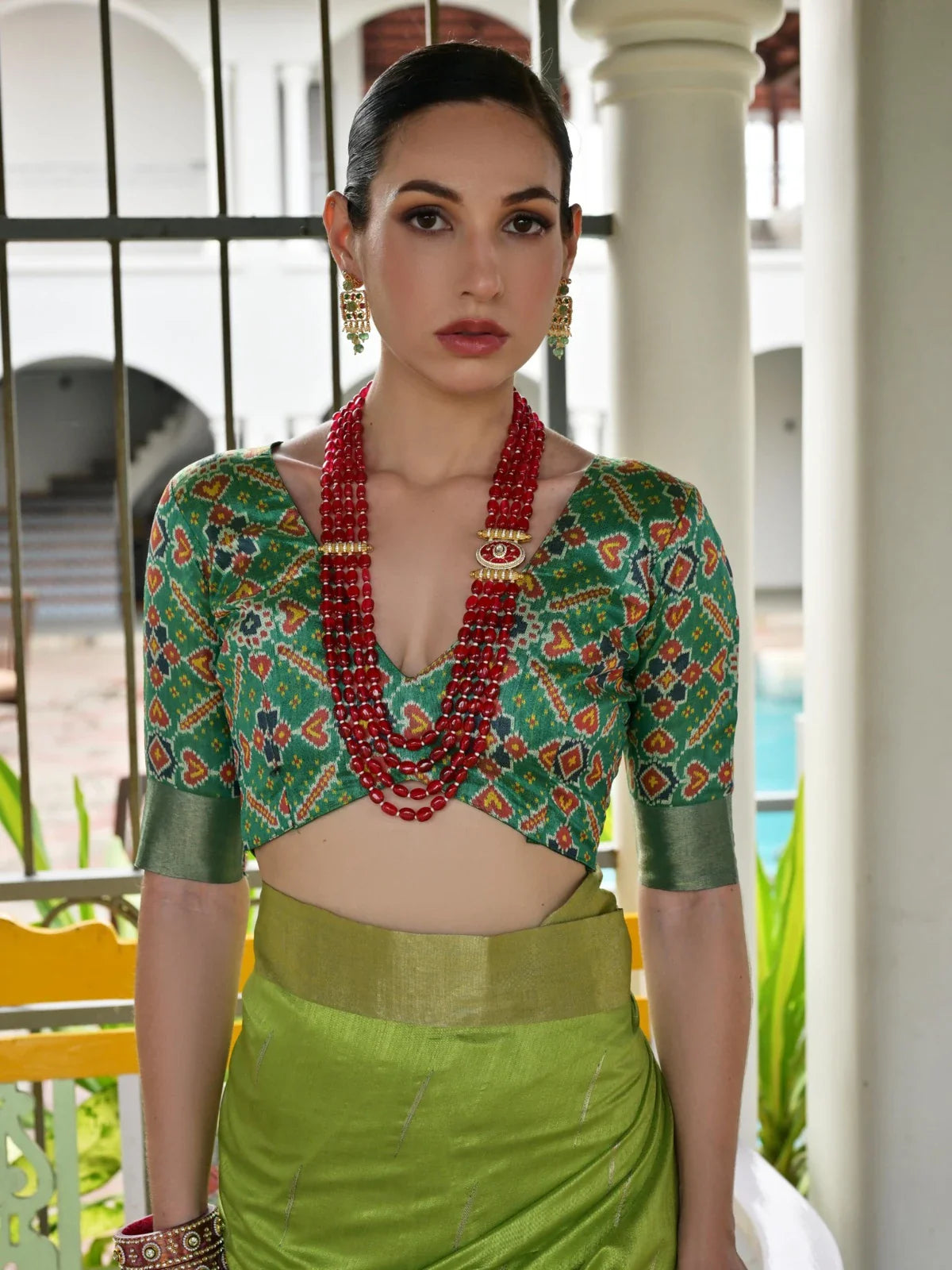 Tarani green saree with blouse and red jewellery in elegant upper body pose