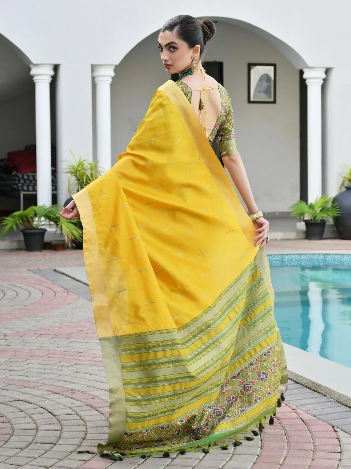 Tarani yellow silk saree back view highlighting pallu tassels and graceful fall