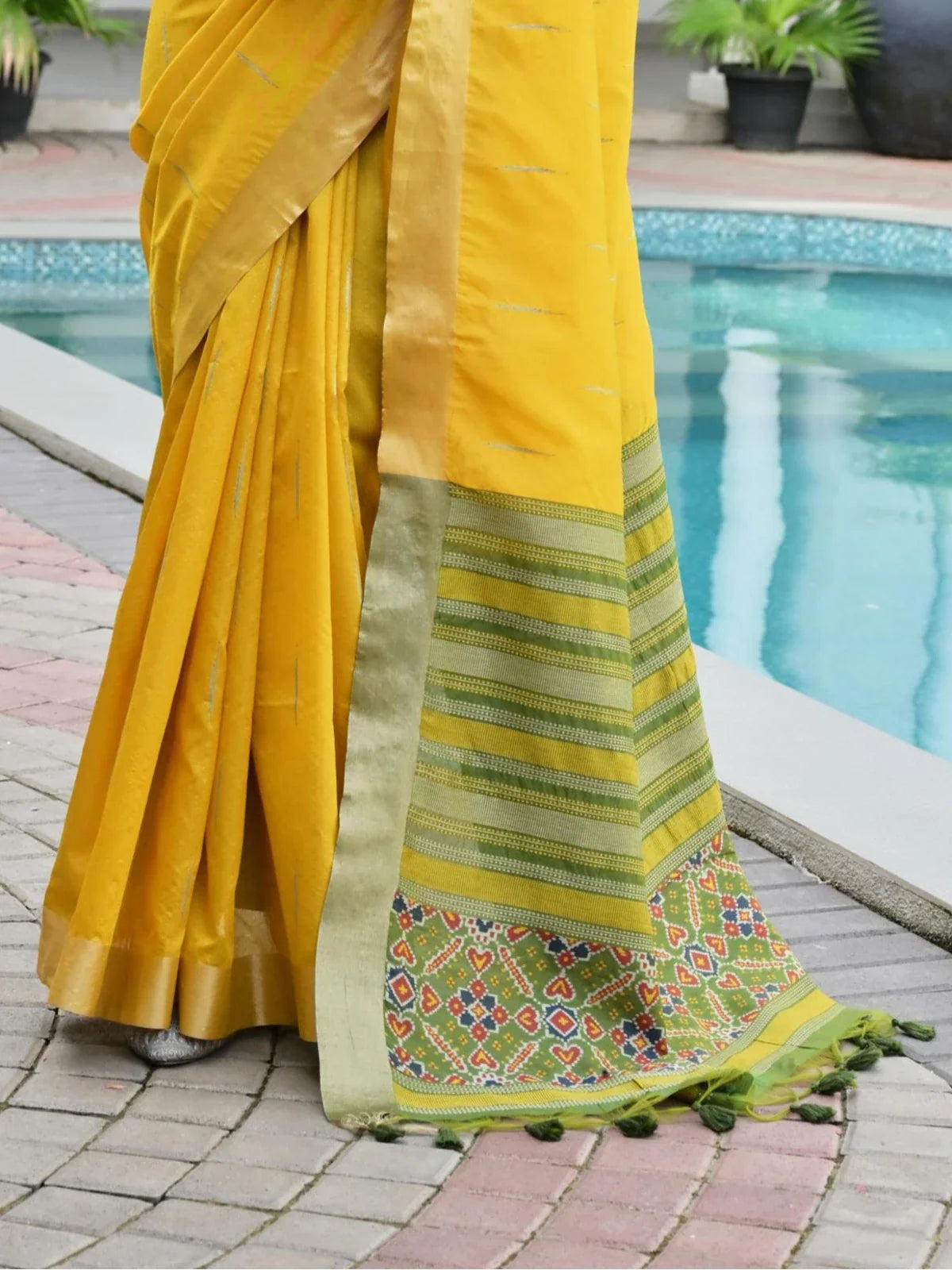 Tarani yellow silk saree fabric closeup showing pallu detailing with traditional motifs