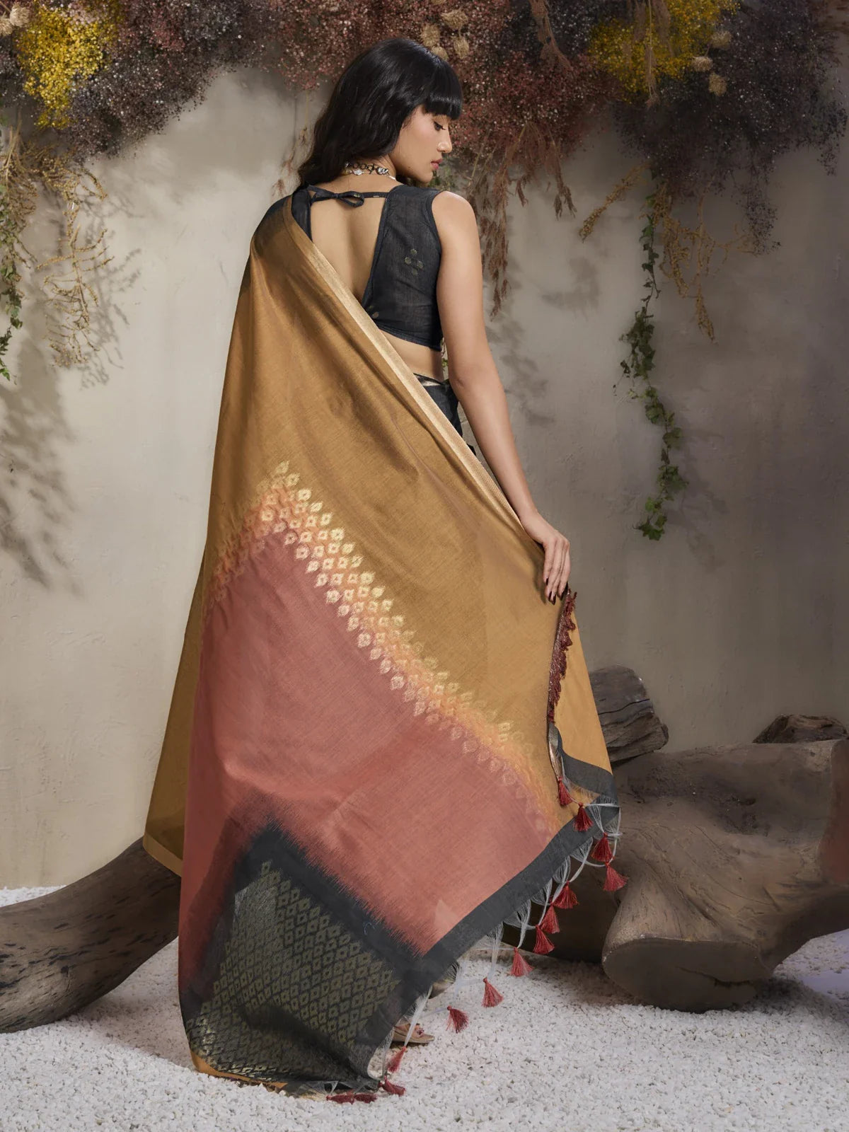 Tarani saree back view showcasing rich pallu design and tassel detailing in warm festive tones