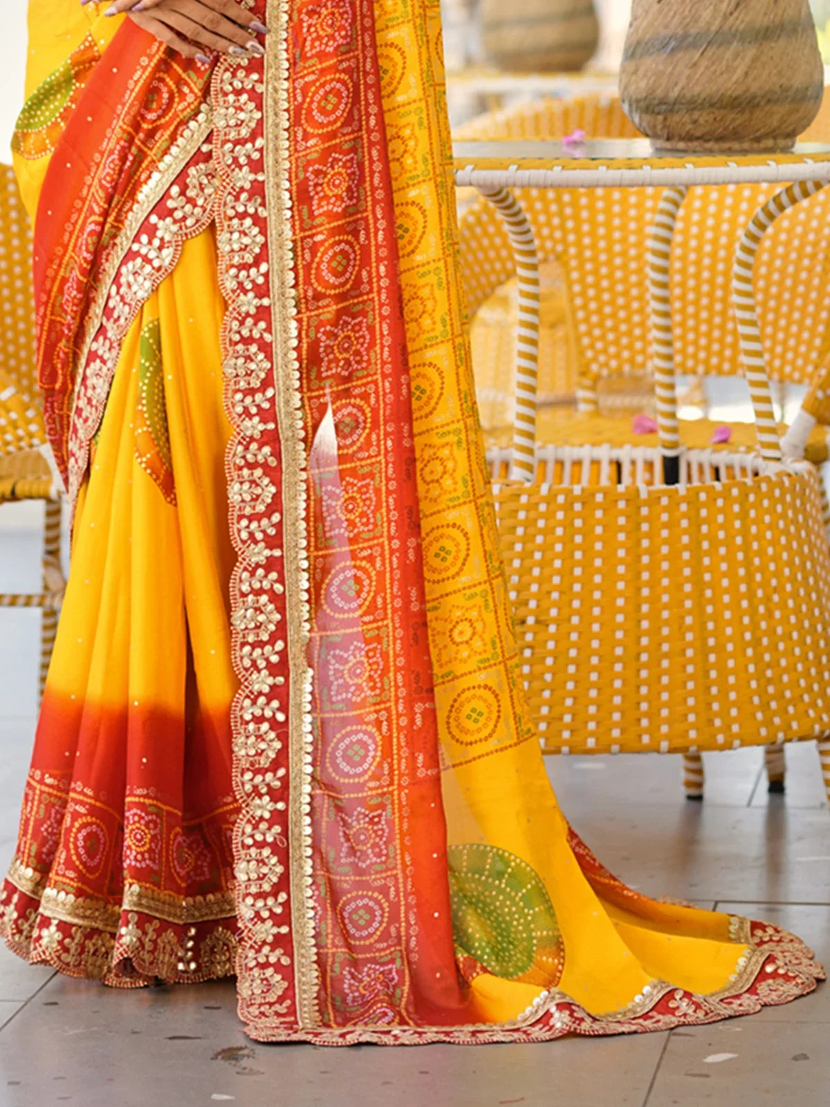Tarani saree closeup showing red-gold embroidery border with bandhani dots and mirror work