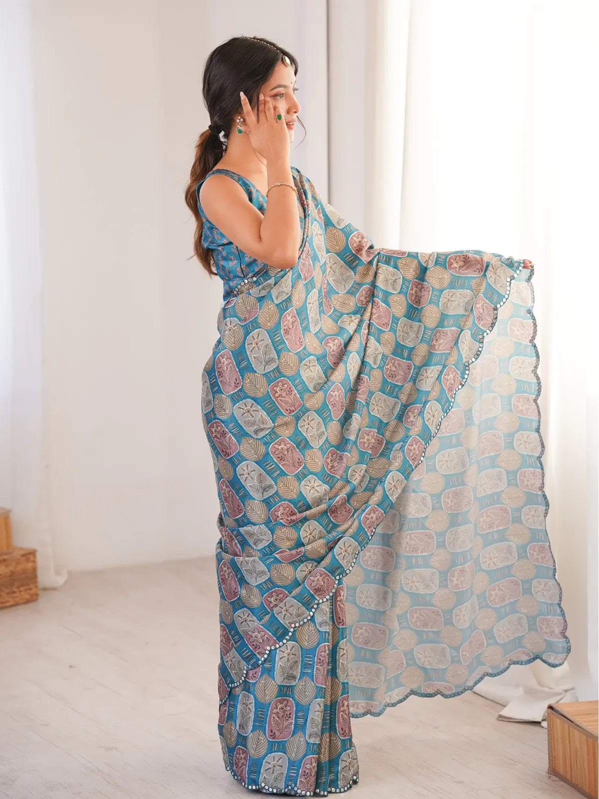 Side pose of model in Tarani blue chinnon saree with festive mirror work