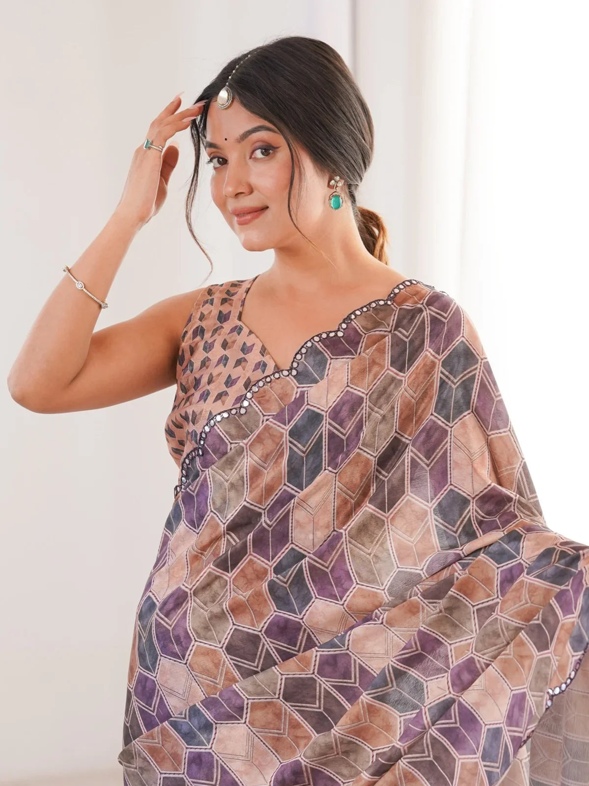 Tarani close-up of model wearing brown chinnon saree with mirror work border and printed blouse