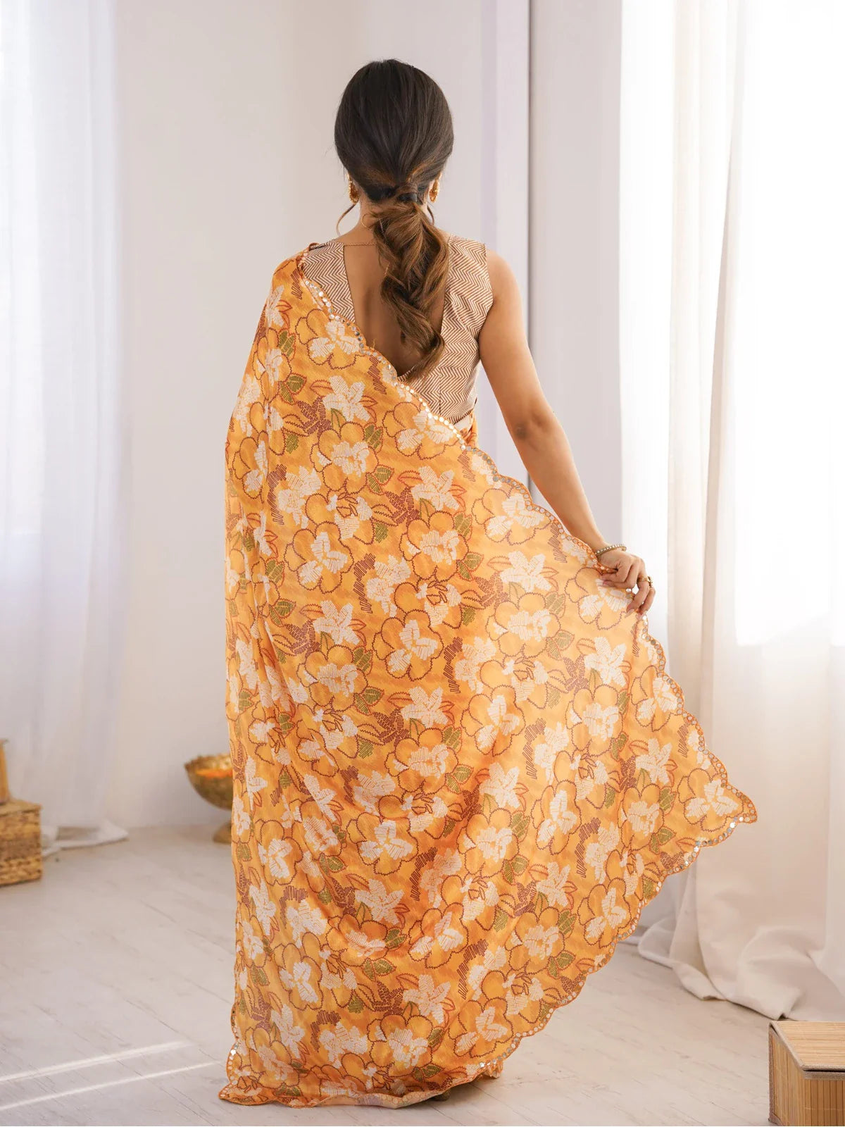 Back view of Tarani orange chinnon saree with floral pallu drape