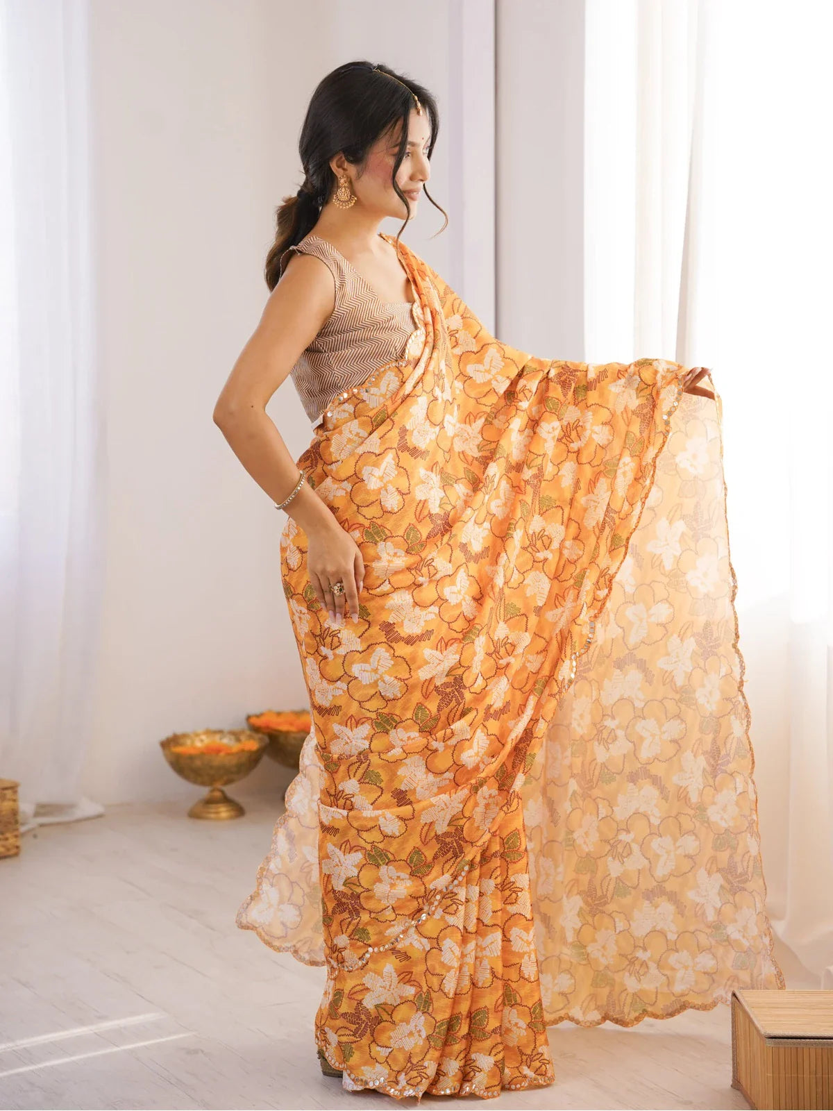 Side pose of model in Tarani festive chinnon saree in orange print