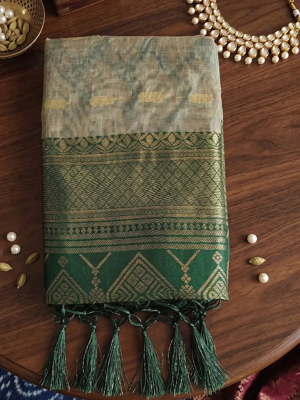 Tarani beige and green cotton silk zari border saree folded fabric closeup with woven detailing