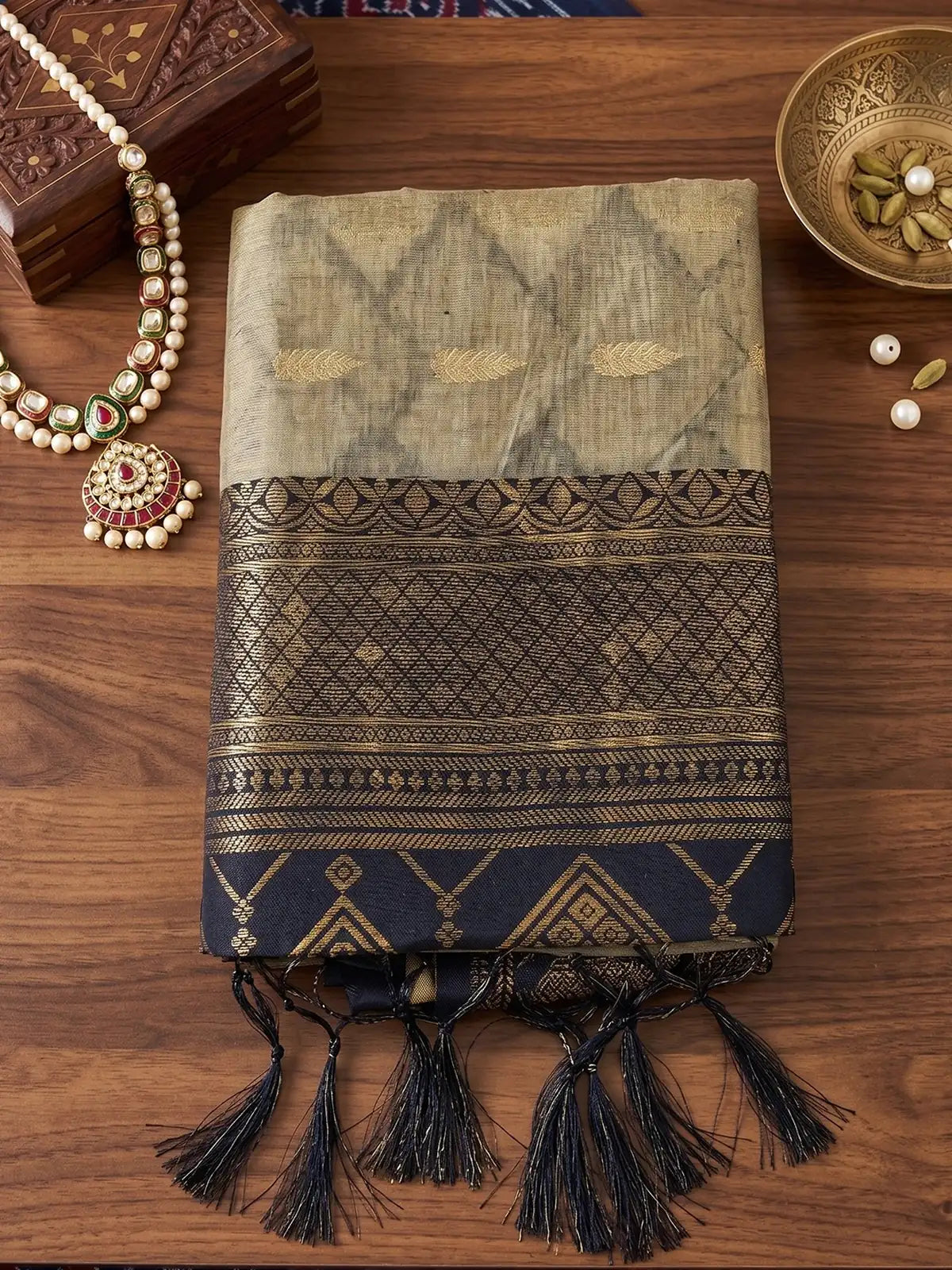 Tarani beige and black cotton silk zari border saree folded fabric closeup with tassel detailing