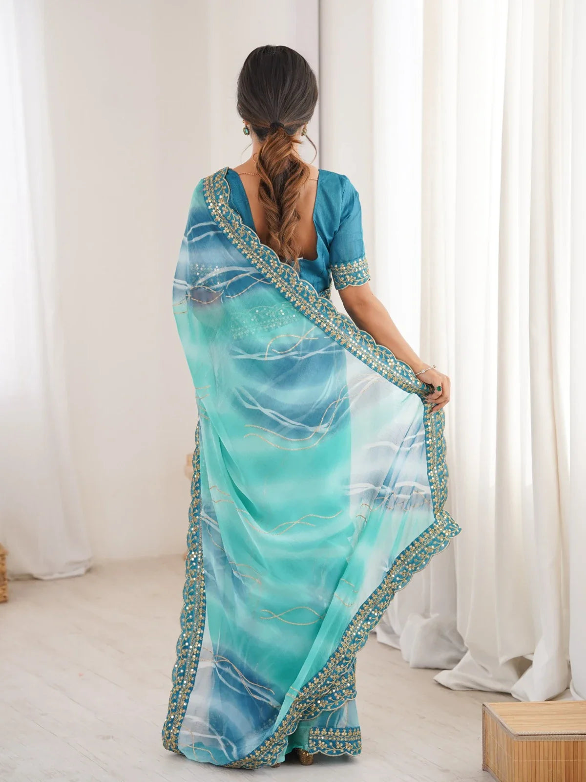 Tarani back view of green georgette saree with embroidered border and elegant blouse design