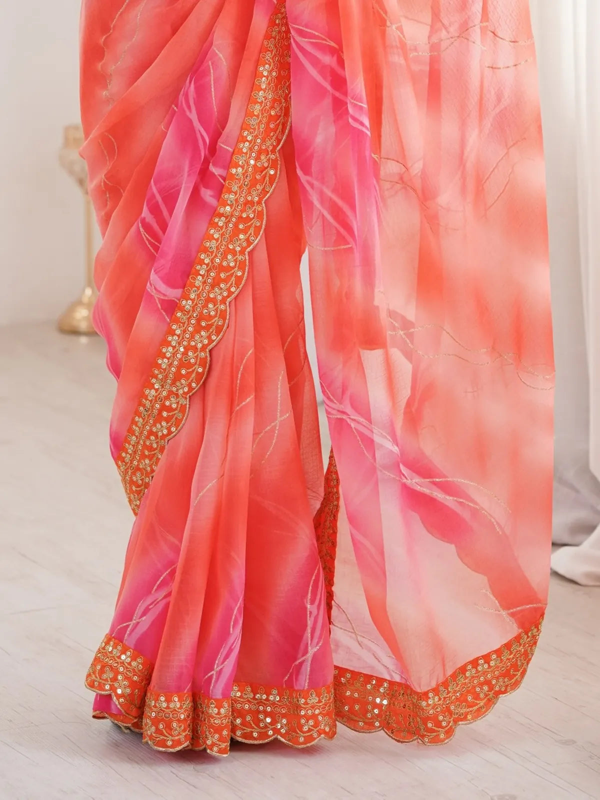 Tarani closeup of orange georgette saree showing gold foil laheriya detailing