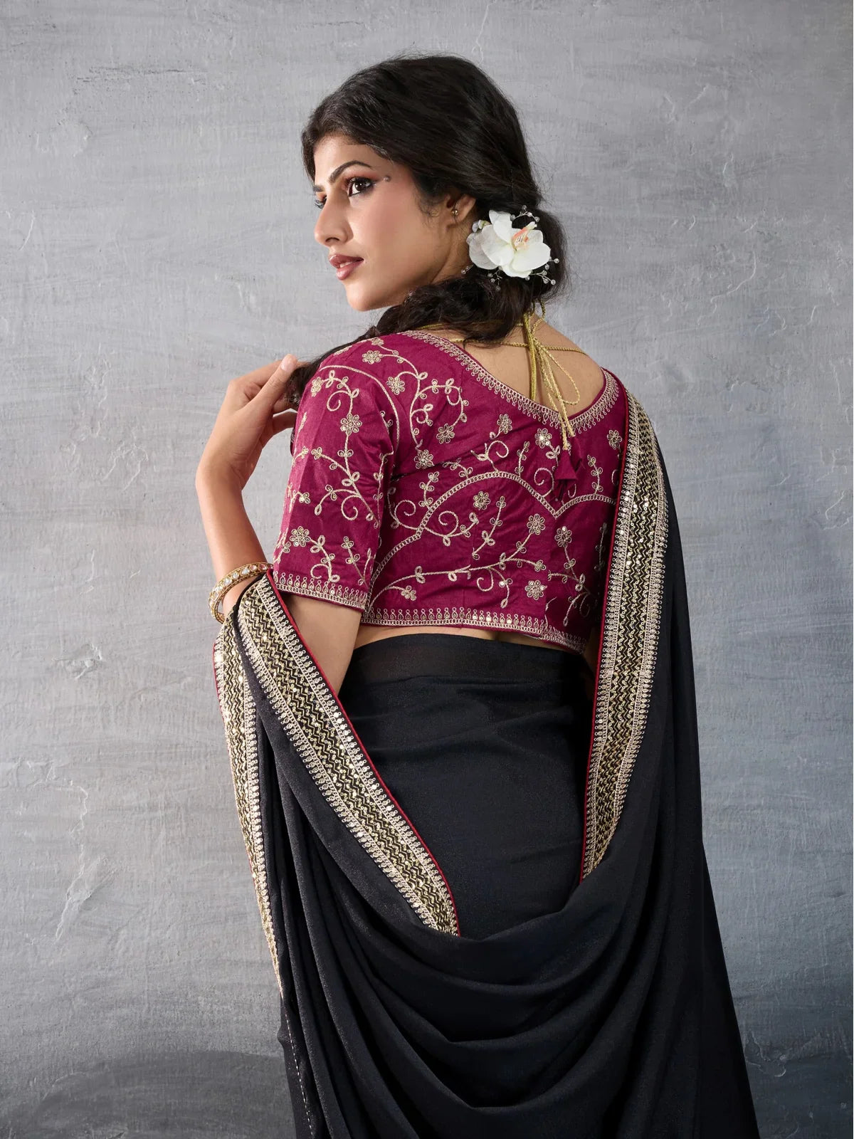 Tarani black georgette saree back blouse view with floral hair accessory and embroidered sleeves