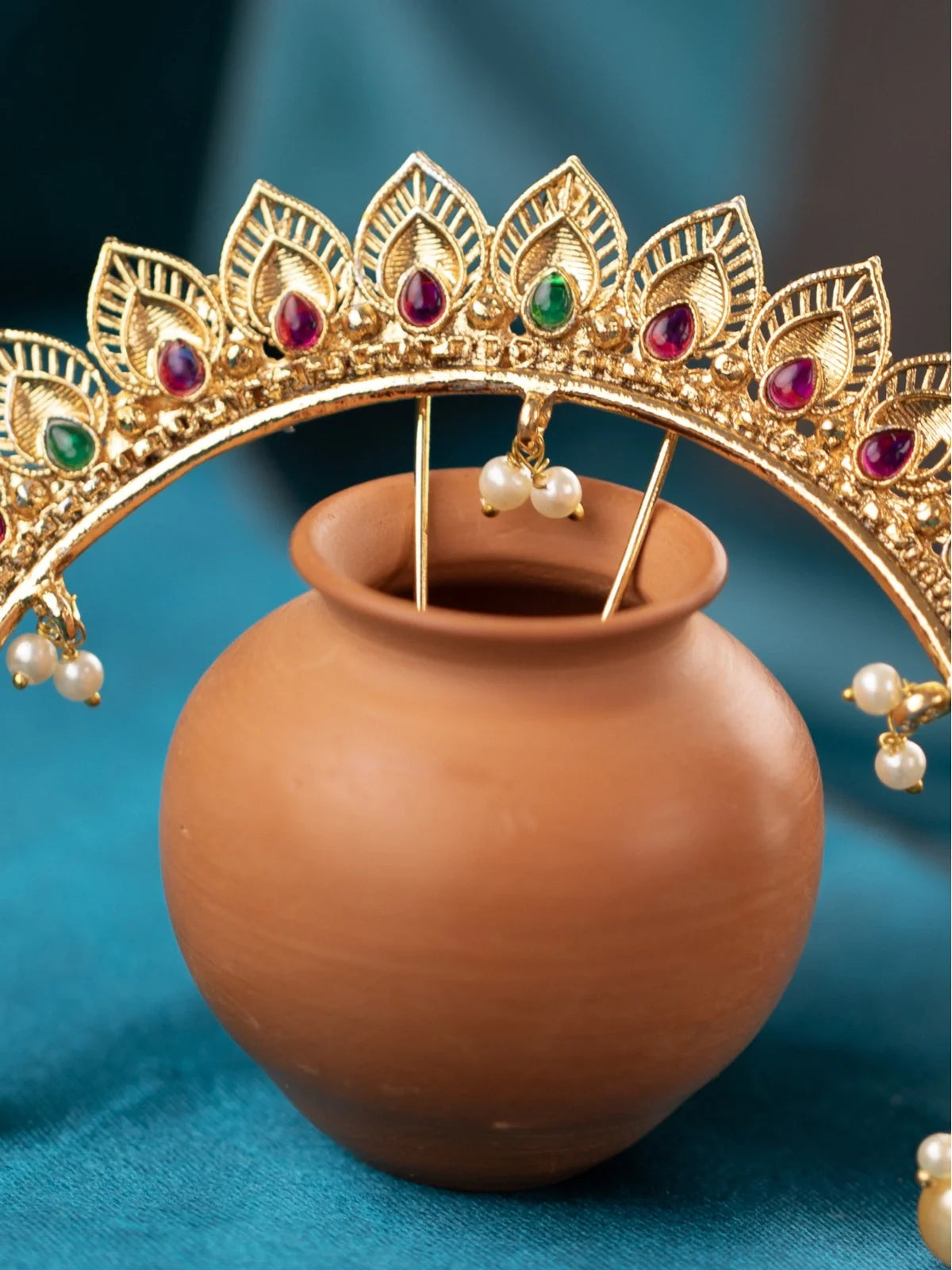 Tarani closeup of gold plated bridal headpiece with red and green stones and pearls