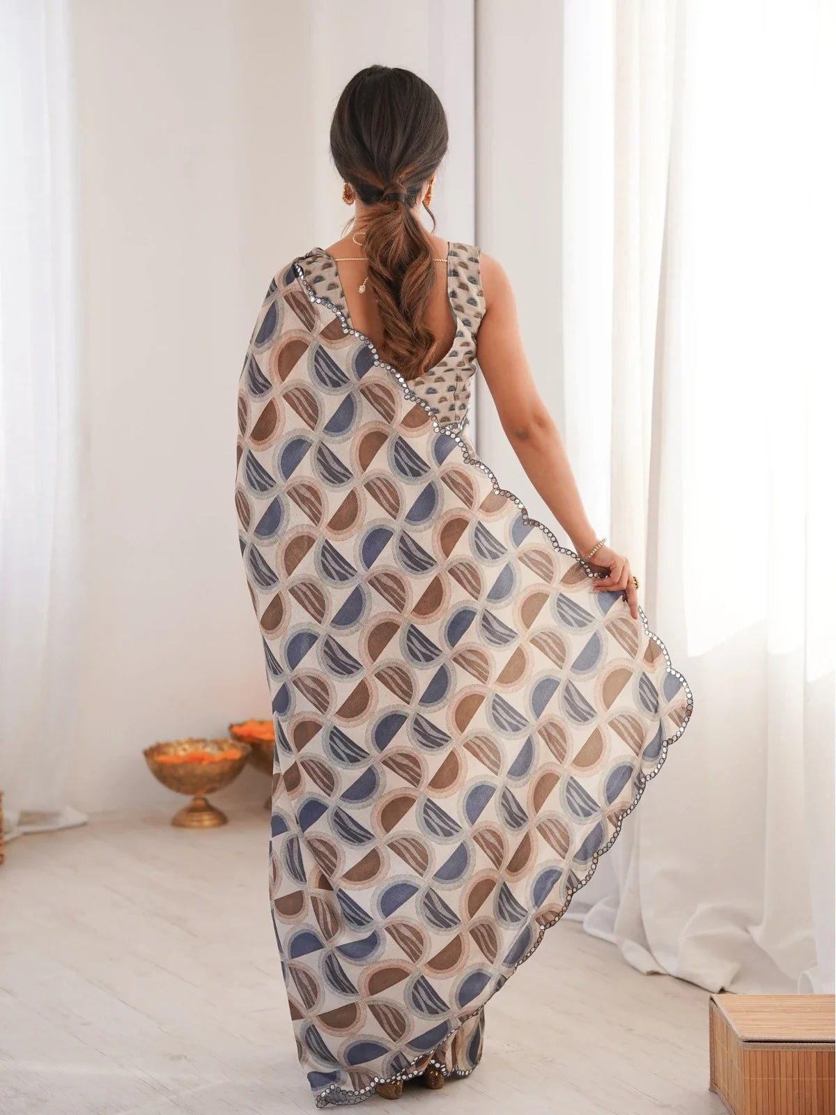 Tarani back view of brown chinnon saree showing pallu flow and designer printed blouse