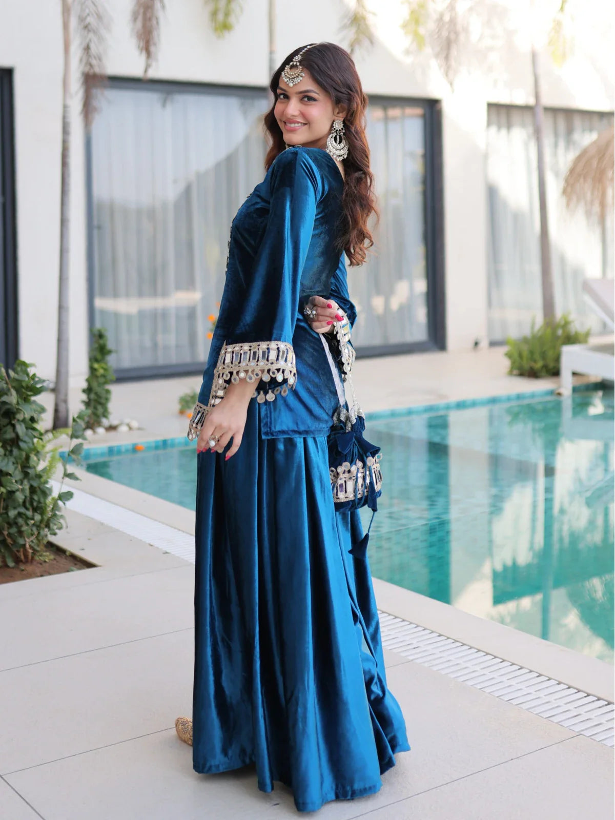 Tarani mirror work blue ice velvet dress side pose with batwa and jhumkas near poolside